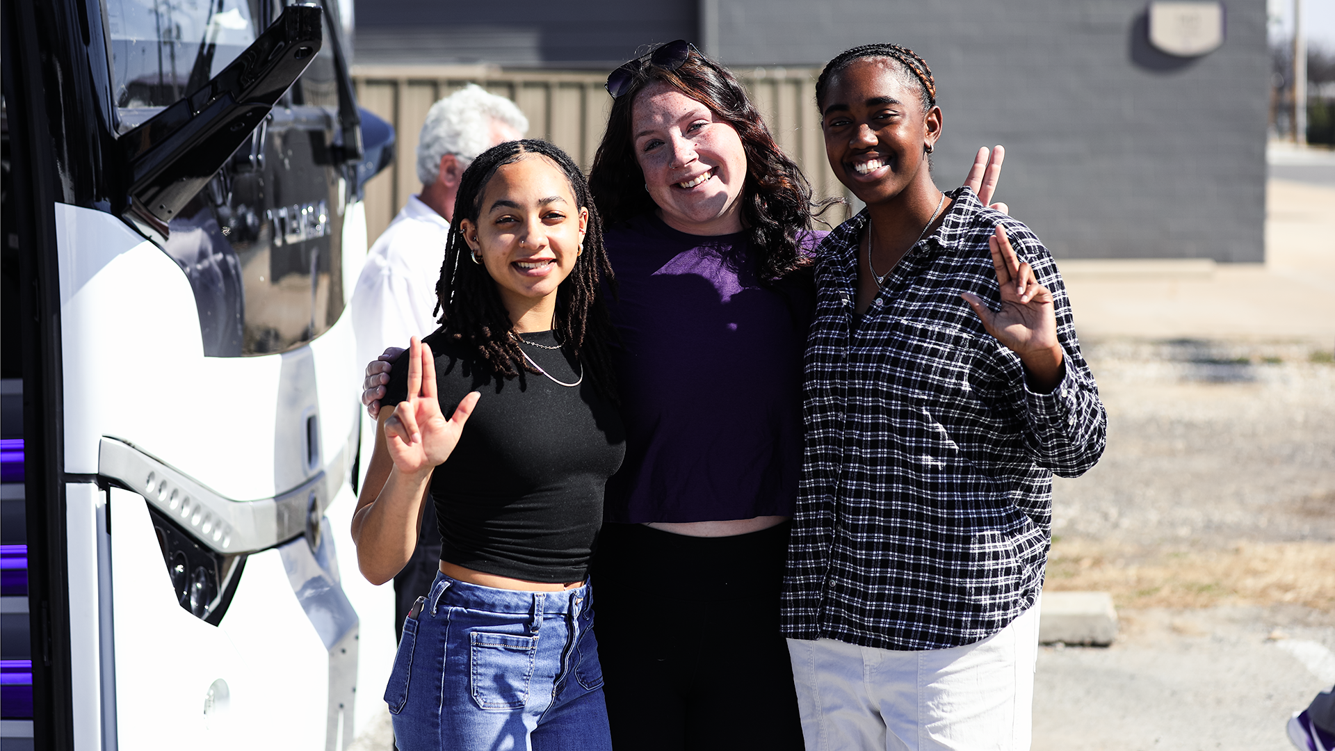 Three Tarleton State athlets smiling before getting on the bus