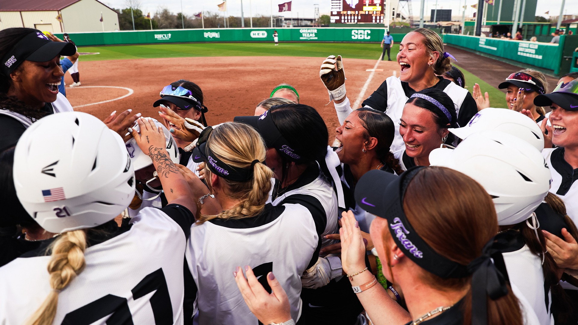 Texan Softball celebrating after Scarlett Poore hits game-winning grand slam against Texas State.