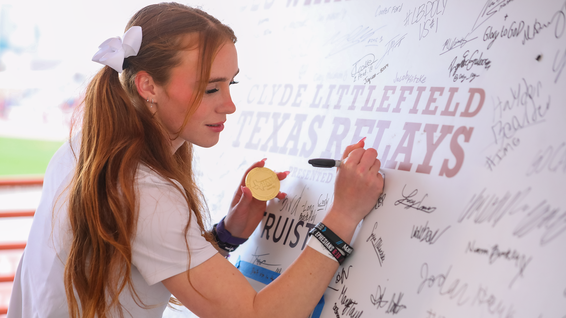 Victoria Cameron signing Texas Relays board with gold medal