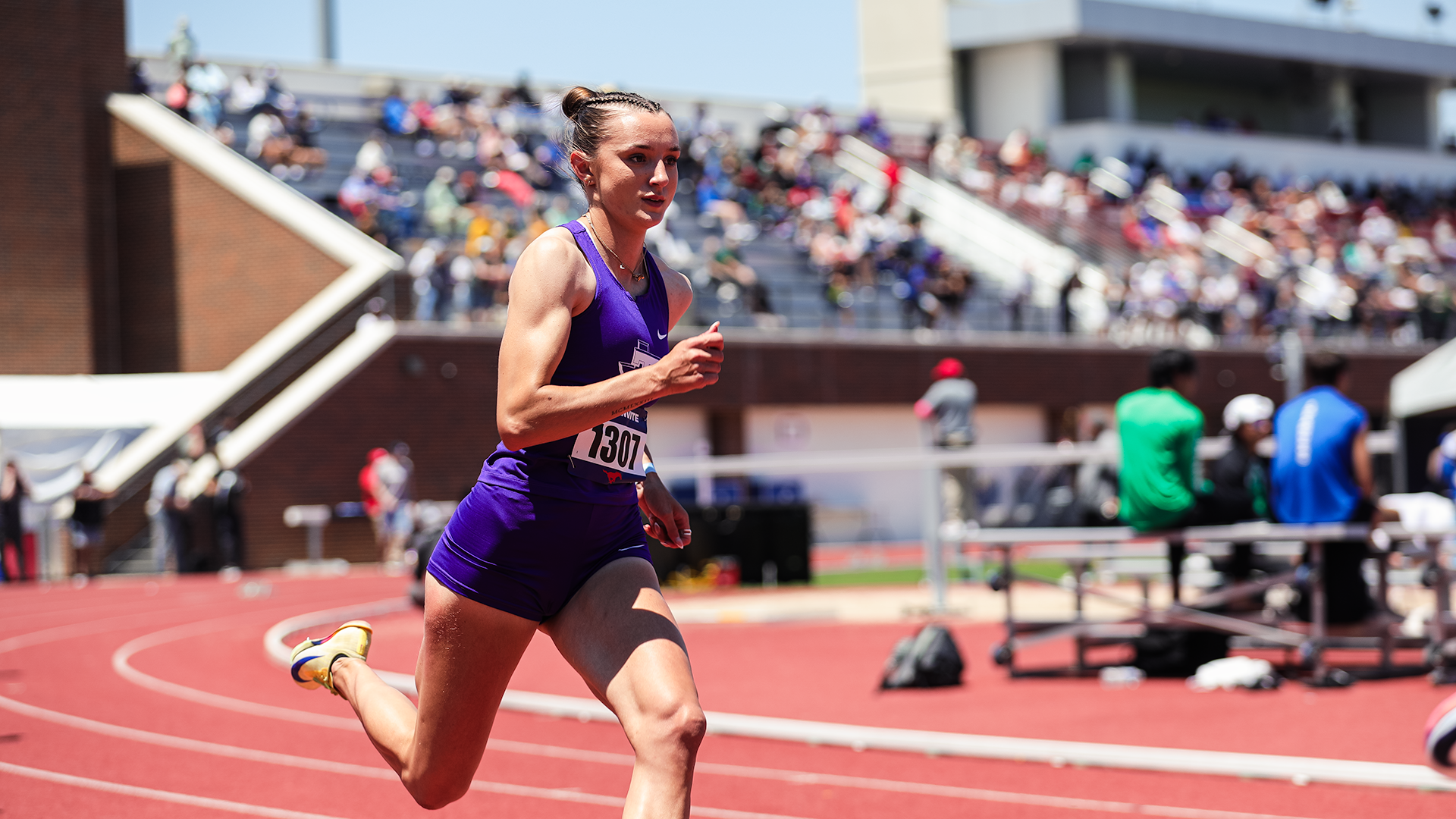 Emma Holmes sprinting in the 400 meters with the stadium behind her