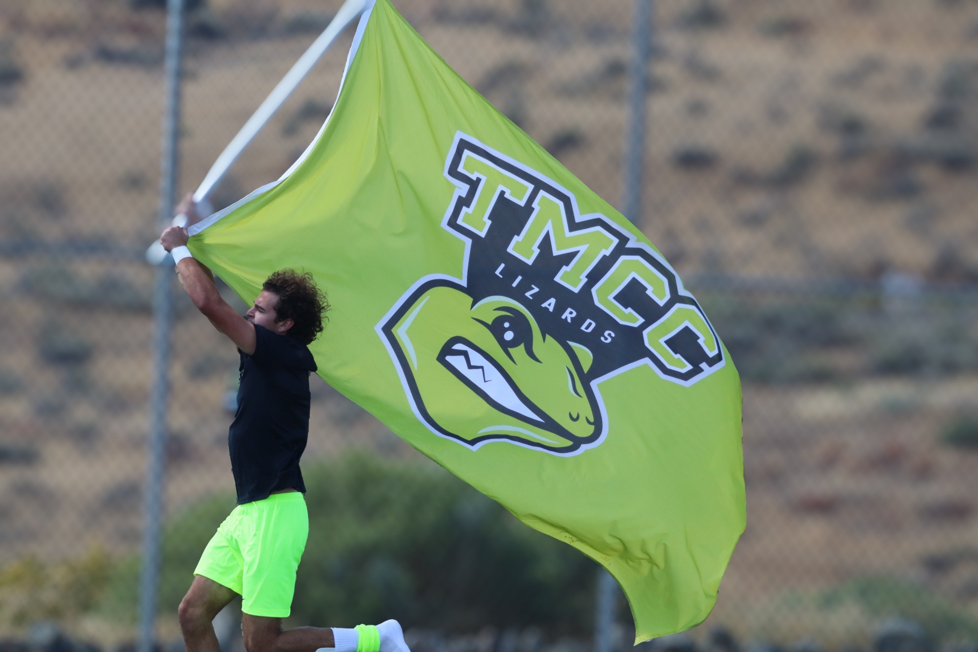 Men's soccer goalie number 1 Sawyer Morris running on the field with TMCC Athletics flag