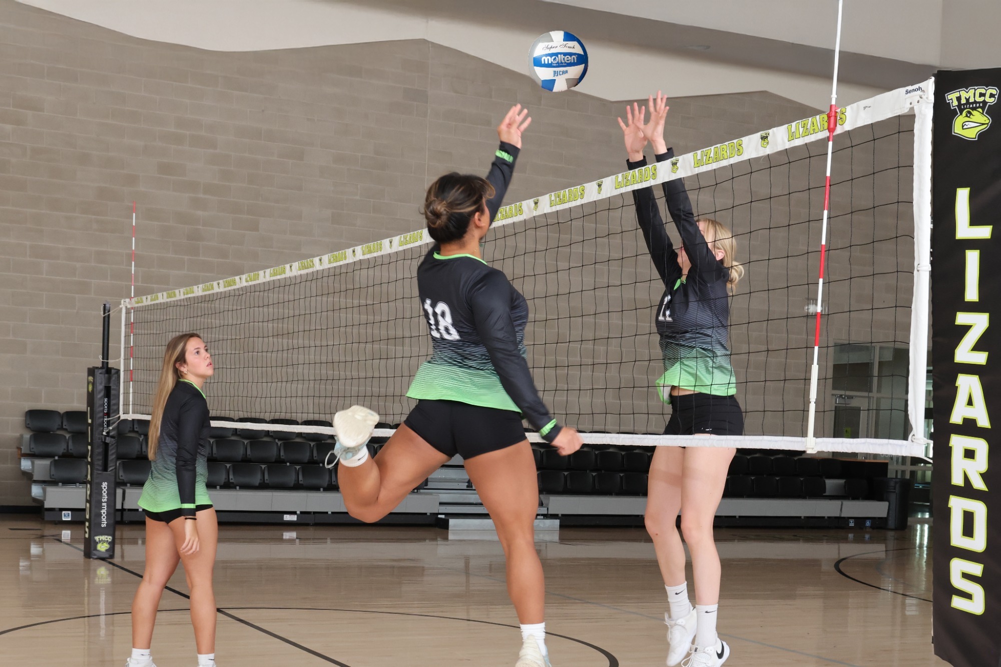 TMCC women’s volleyball players practice at the net.