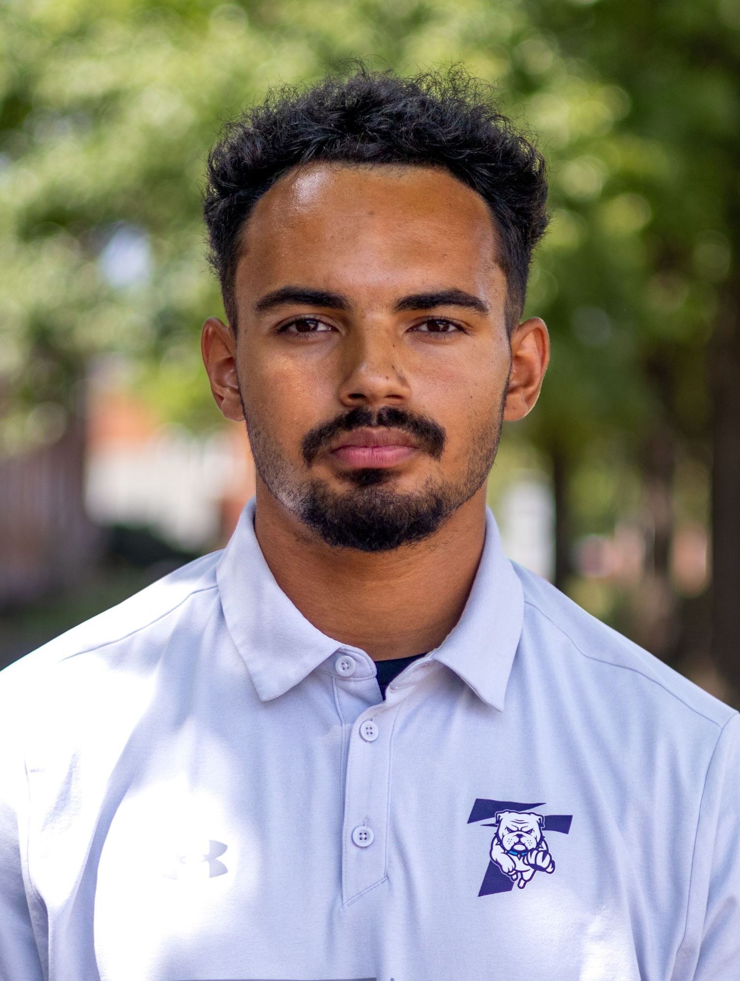 Tyson Bochert Staff Headshot in a branded grey polo with a Bulldogs logo