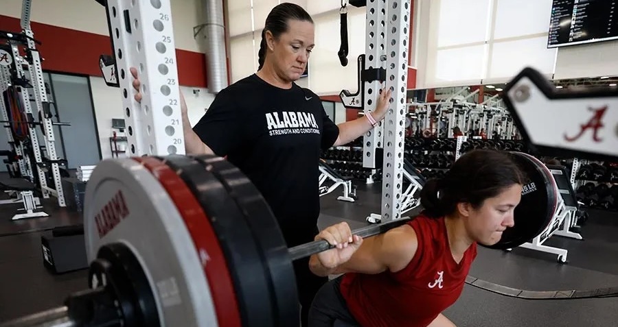 Individual coaching a student-athlete for proper weight lifting 