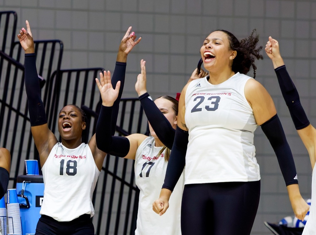 TWU Volleyball players jump up in excitement. 