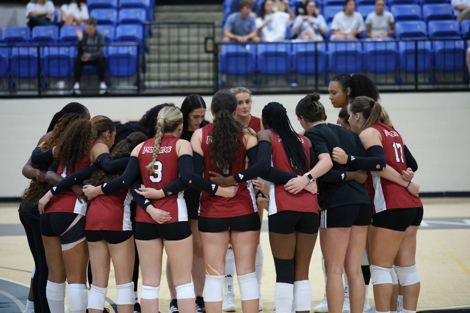 The TWU Volleyball team huddles together on the court. 