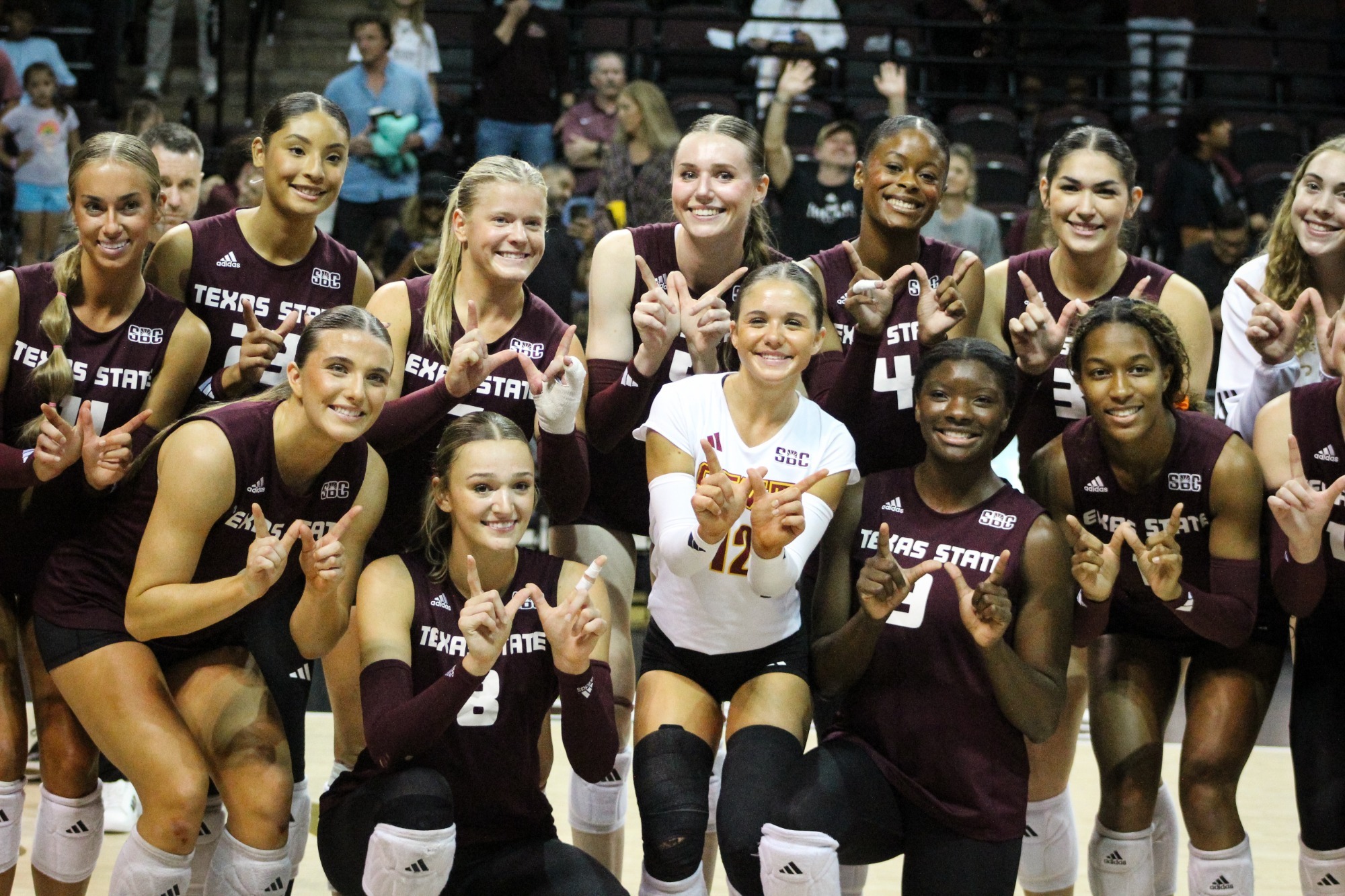 2025 Volleyball team holding up the W sign