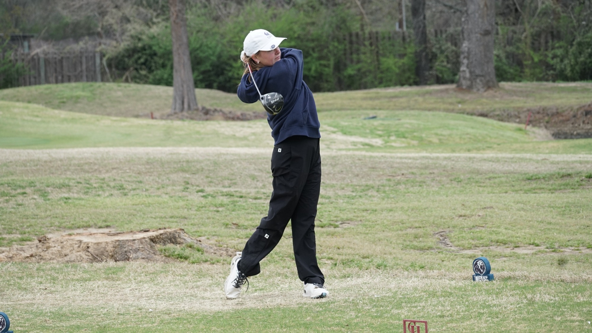 A women's golfer takes a swing at a tournament. 