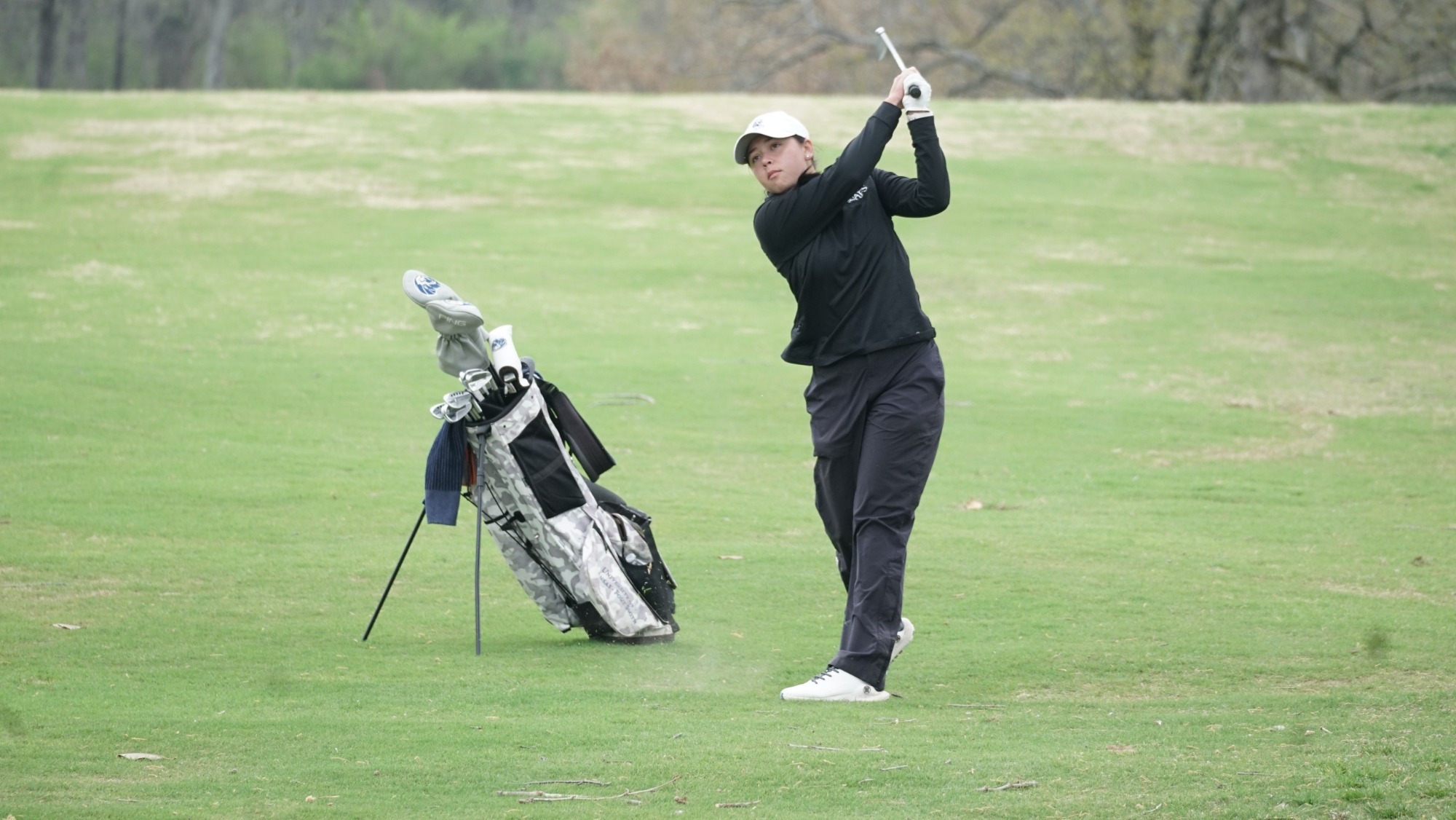 A women's golfer takes a swing at a tournament. 