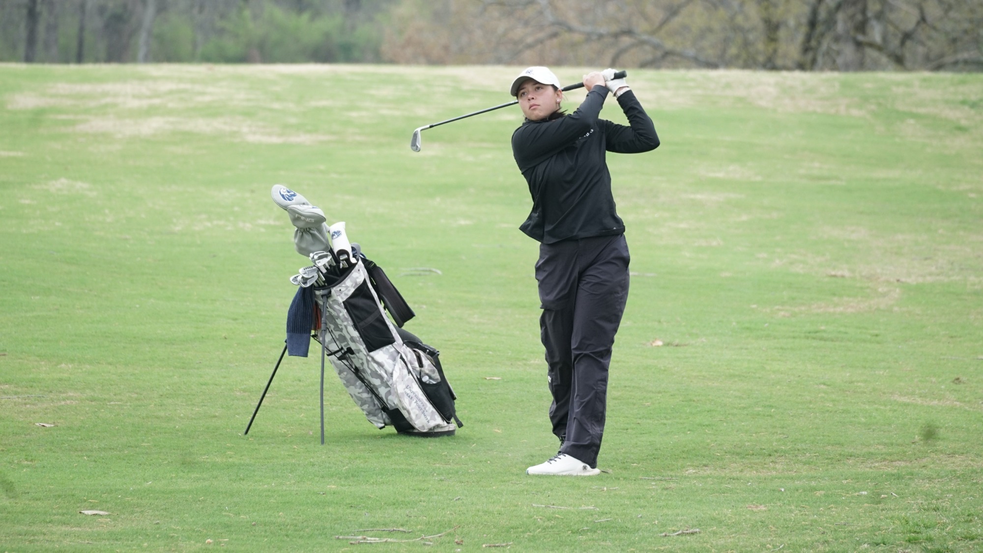 A women's golfer takes a swing at a tournament. 