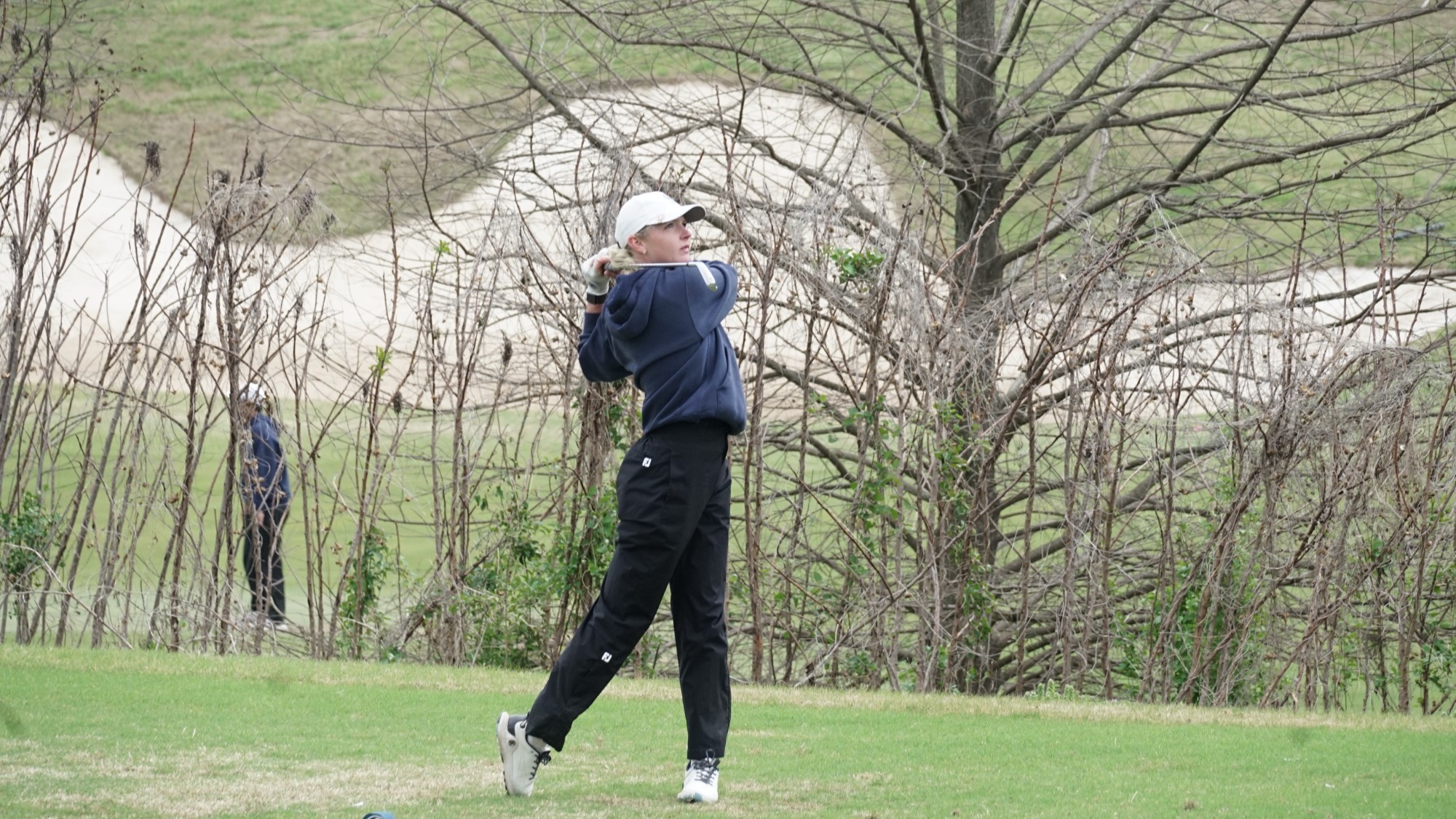 A women's golfer takes a swing at a tournament. 