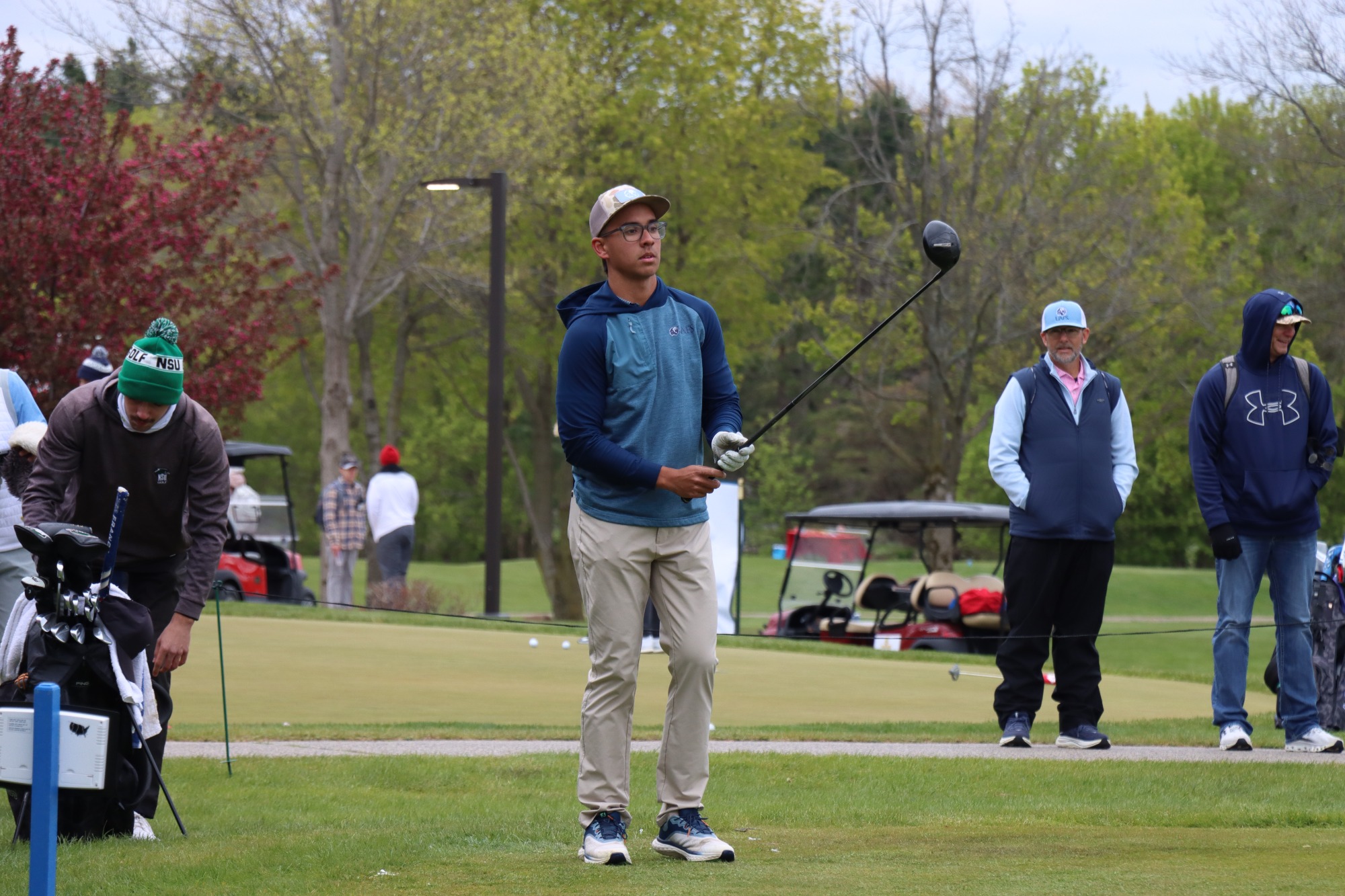 A men's golfer in a blue shirt and black pants swings at the NCAA II Central Regional. 