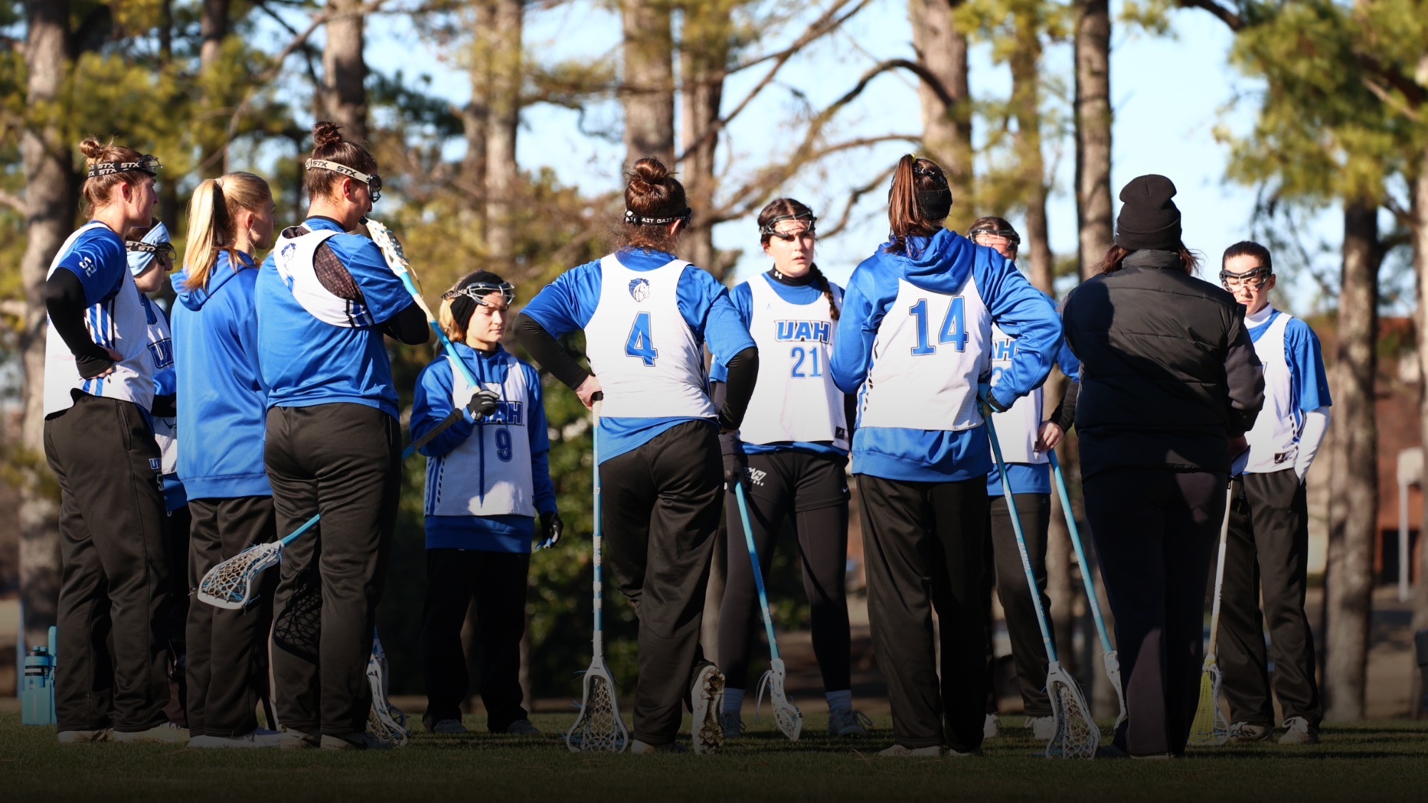 Women's lacrosse team in a huddle at practice