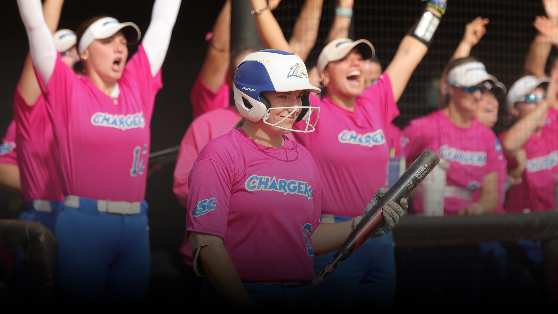 Allie Yeary smiling with softball team celebrating behind her