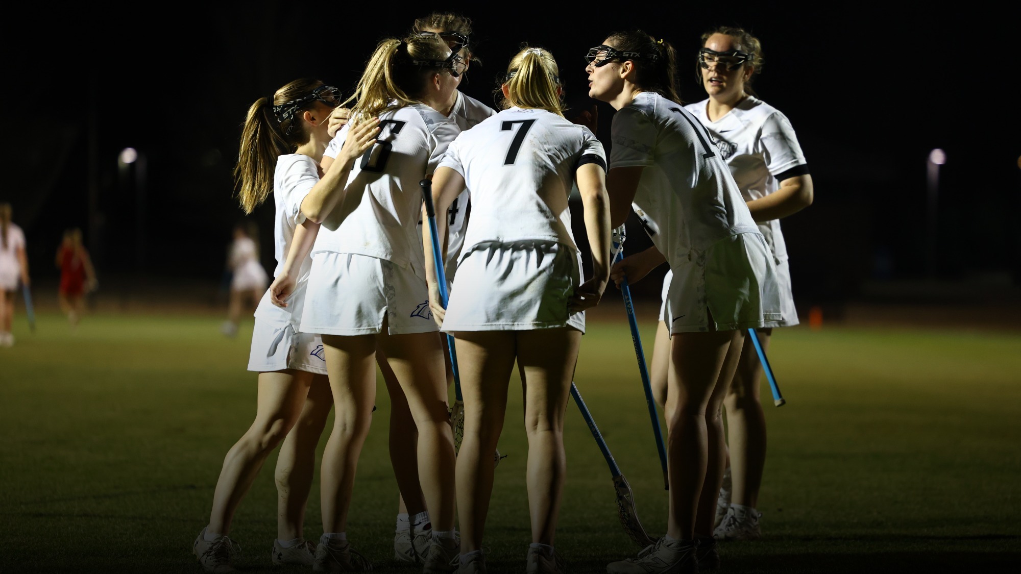 Women's lacrosse team huddled after a goal