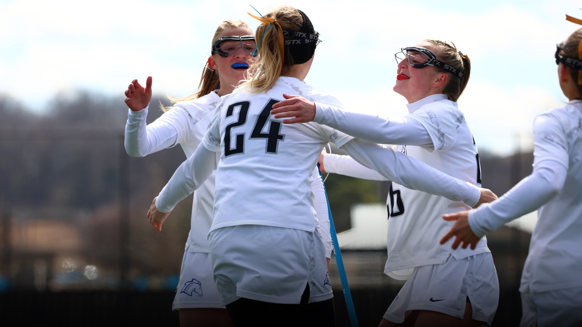 Women's lacrosse players celebrating a goal