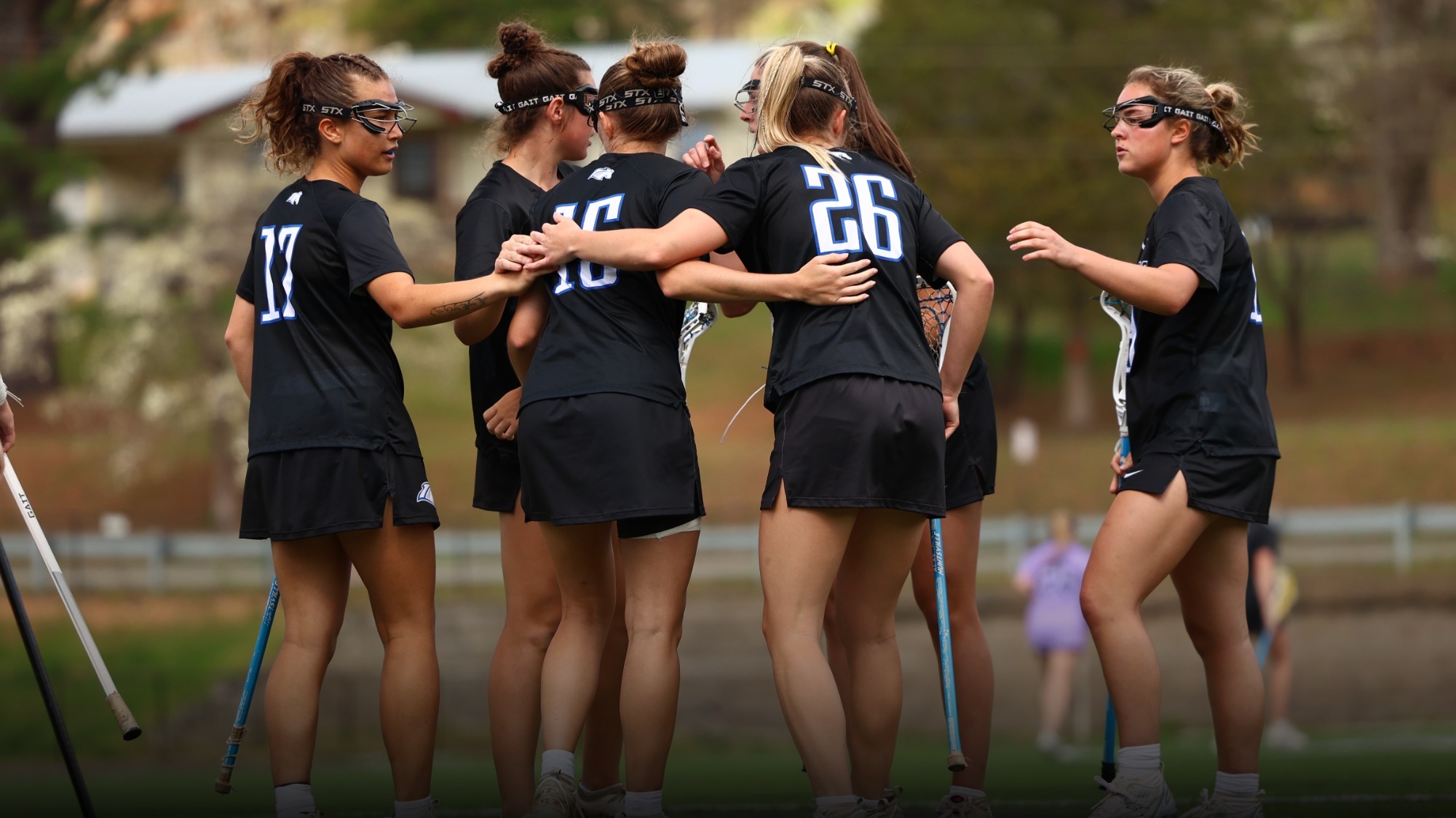 Women's lacrosse team huddled after a goal