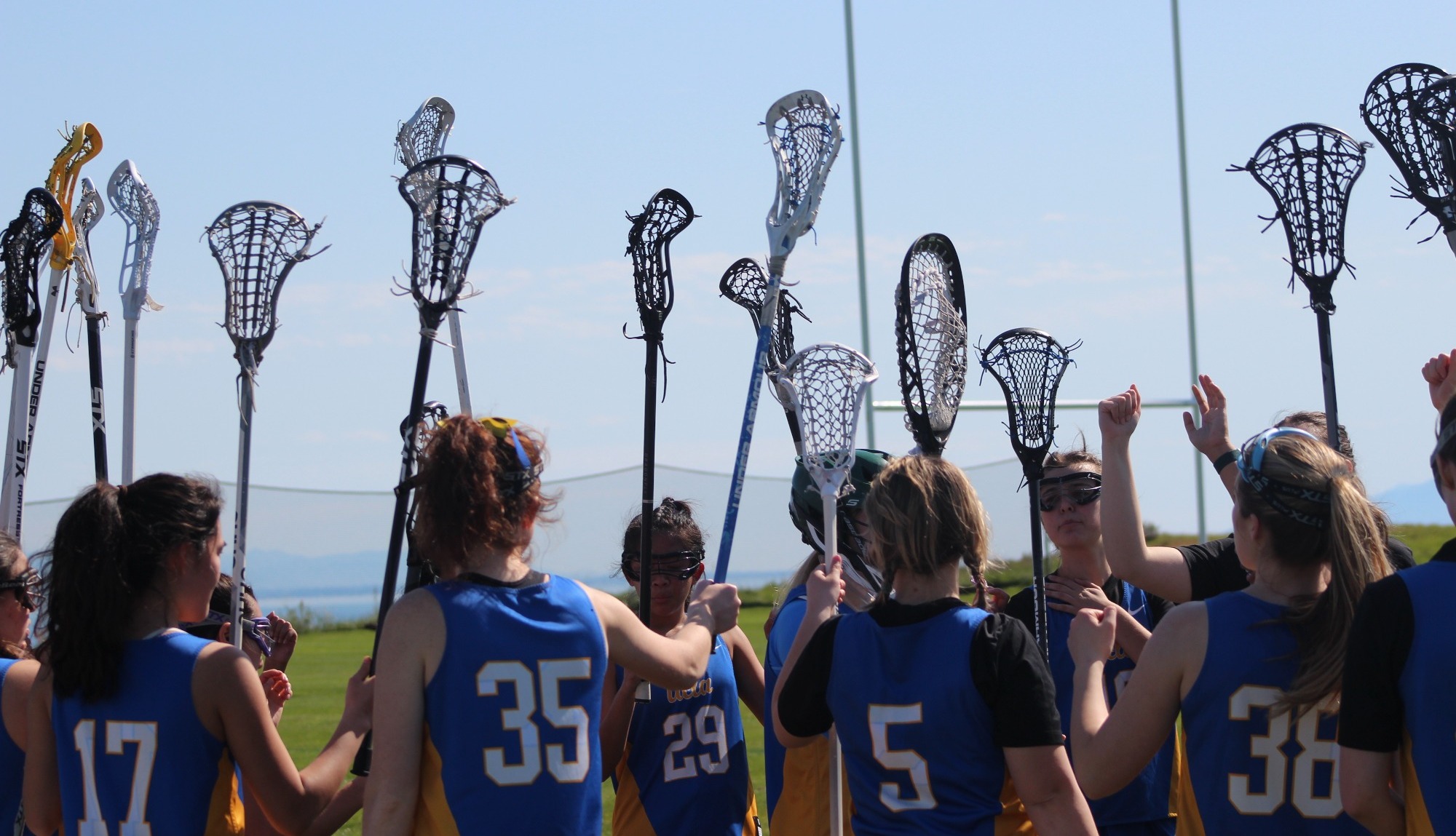 Bruin women's lacrosse players cheering after a timeout before game play starts again.