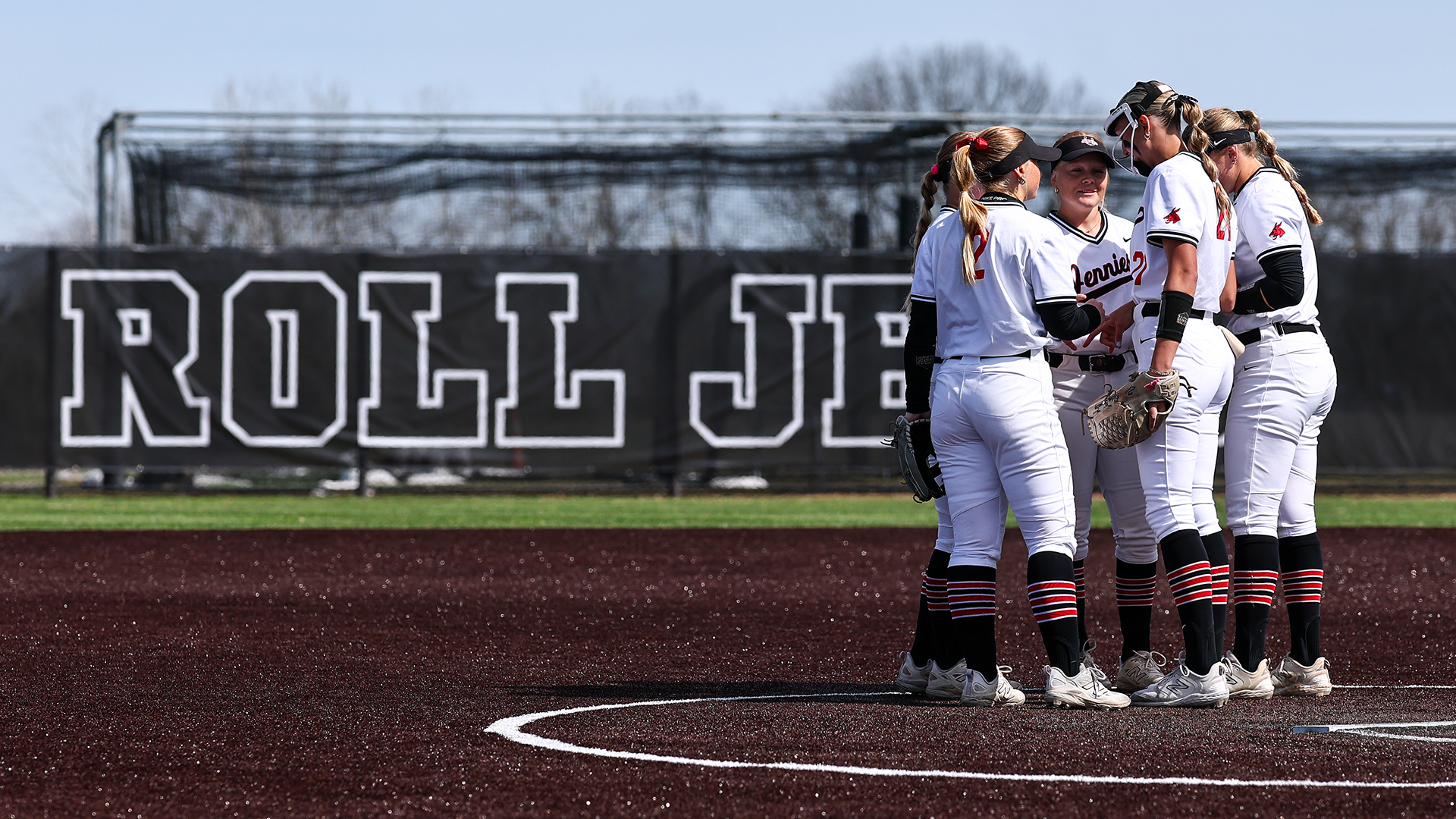 Jennies softball infield huddle on turf at South Recreation Complex 