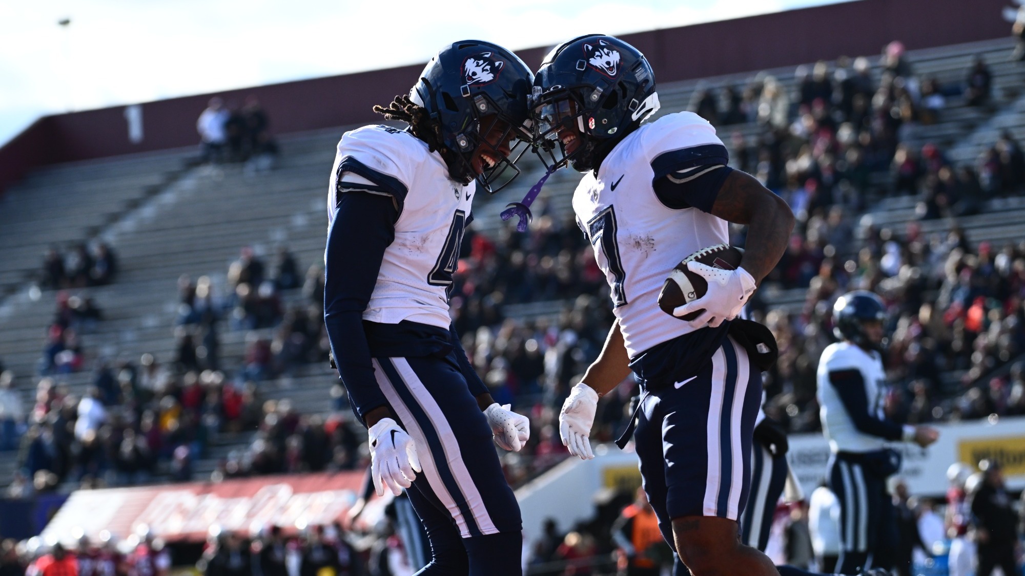 UConn Huskies football teammates celebrating against UMass in the 2024 rivalry game