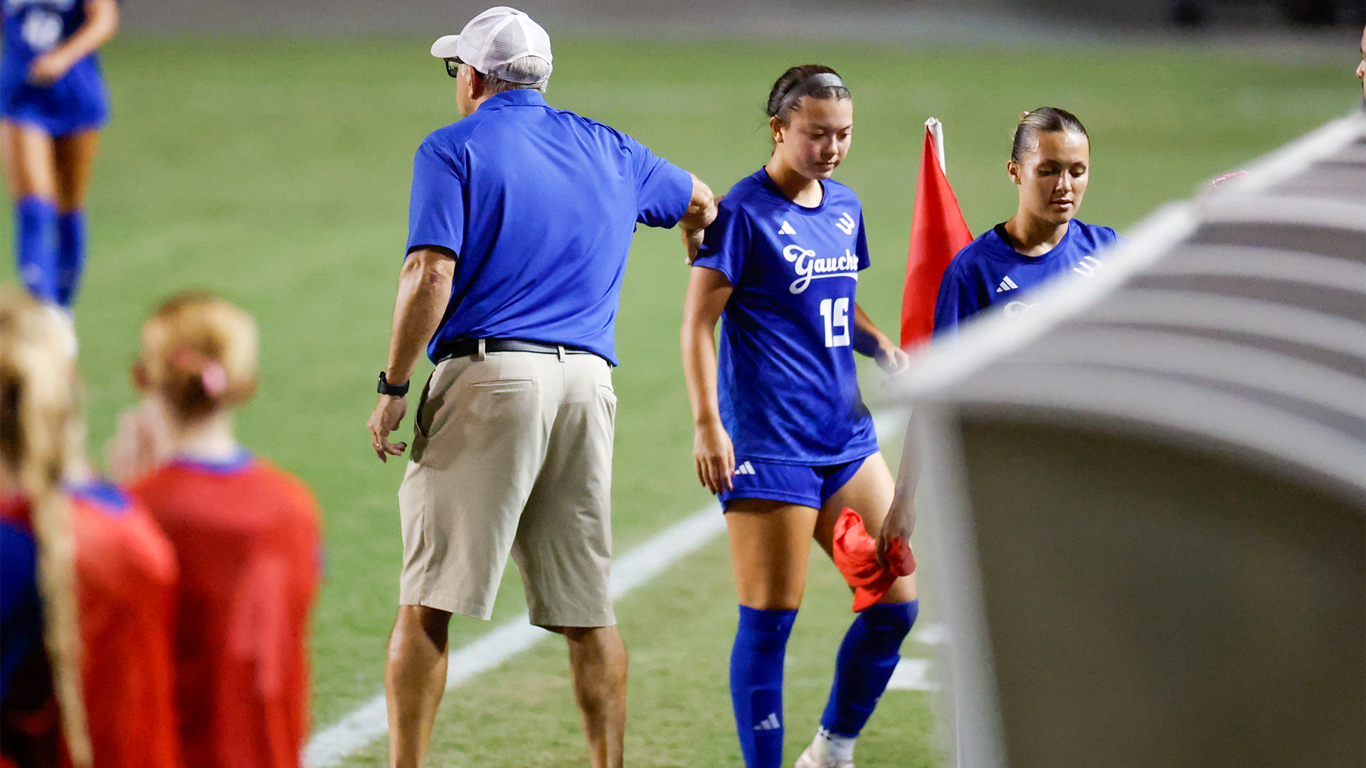 Head Coach Paul Stumpf consoles an athlete coming off the field for a substitution.