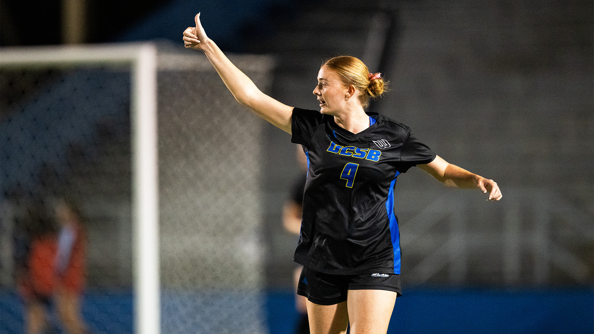 Kate Killer (#4) gives a thumbs up to the bench as she is jogging on the field. 