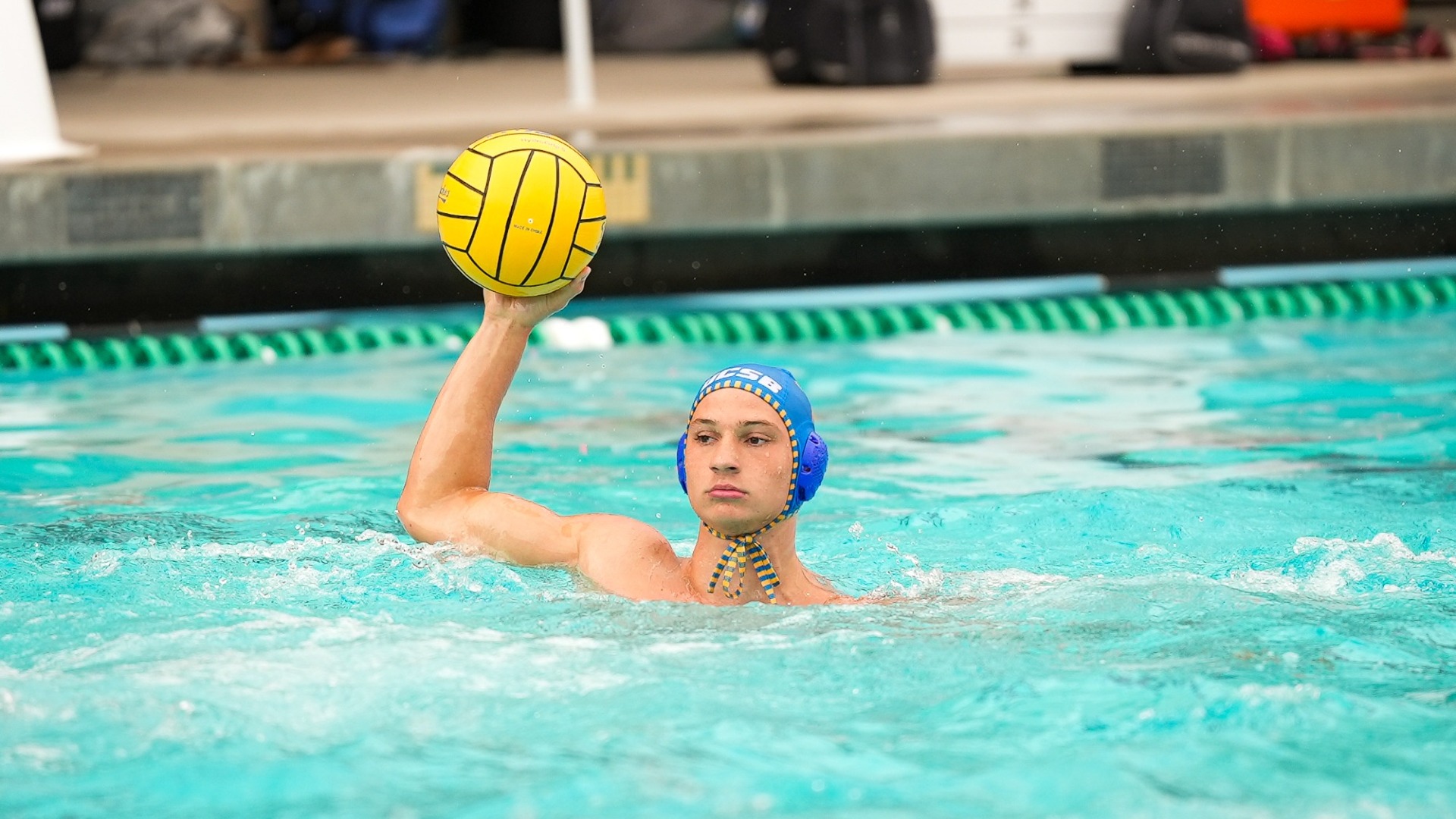 Luigi Canepa holds the ball up out of the water, his arm at a right angle, as he scans for a teammate to pass too.