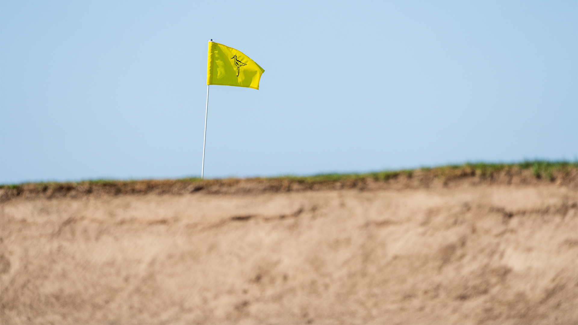 A picture from a low angle in a bunker with a a flag poking above it. 