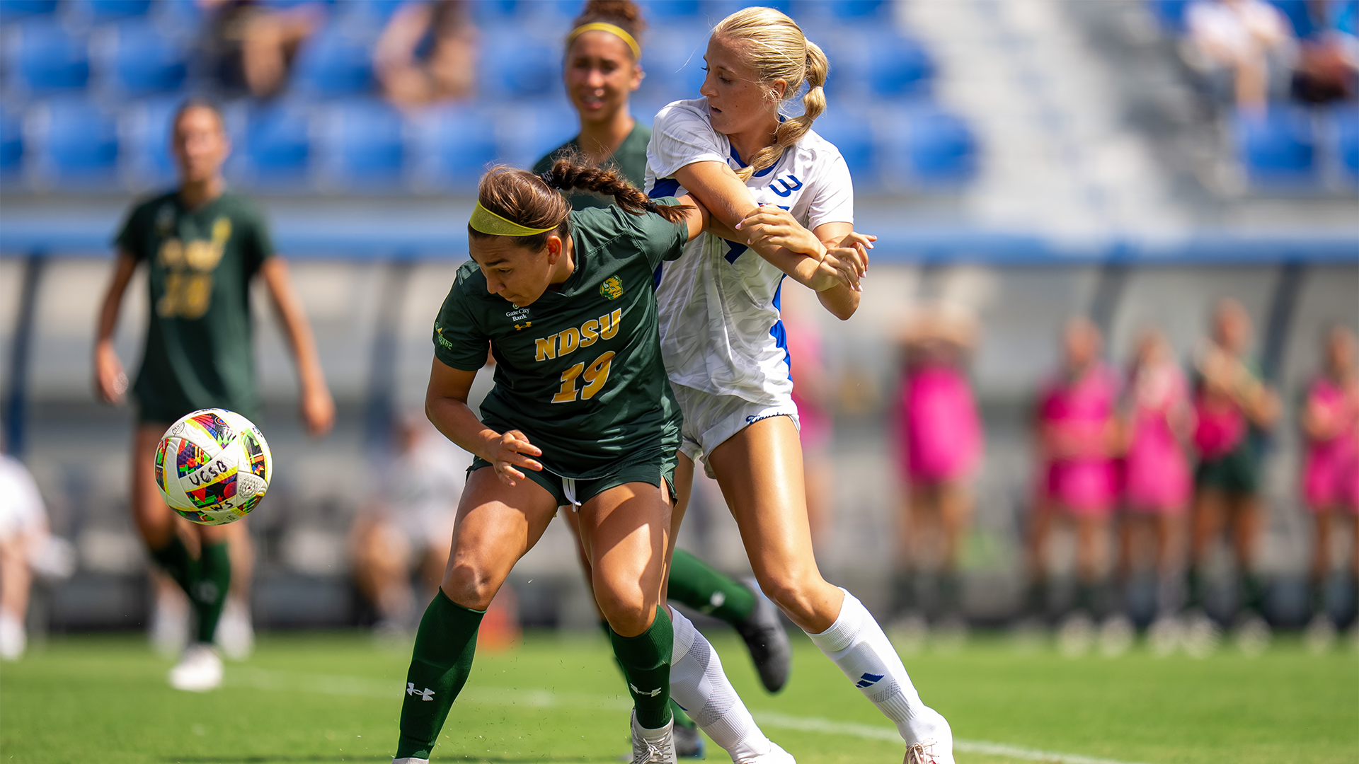 Hailey Tyacke (#24) and wrestles with a defender to fight for a ball.