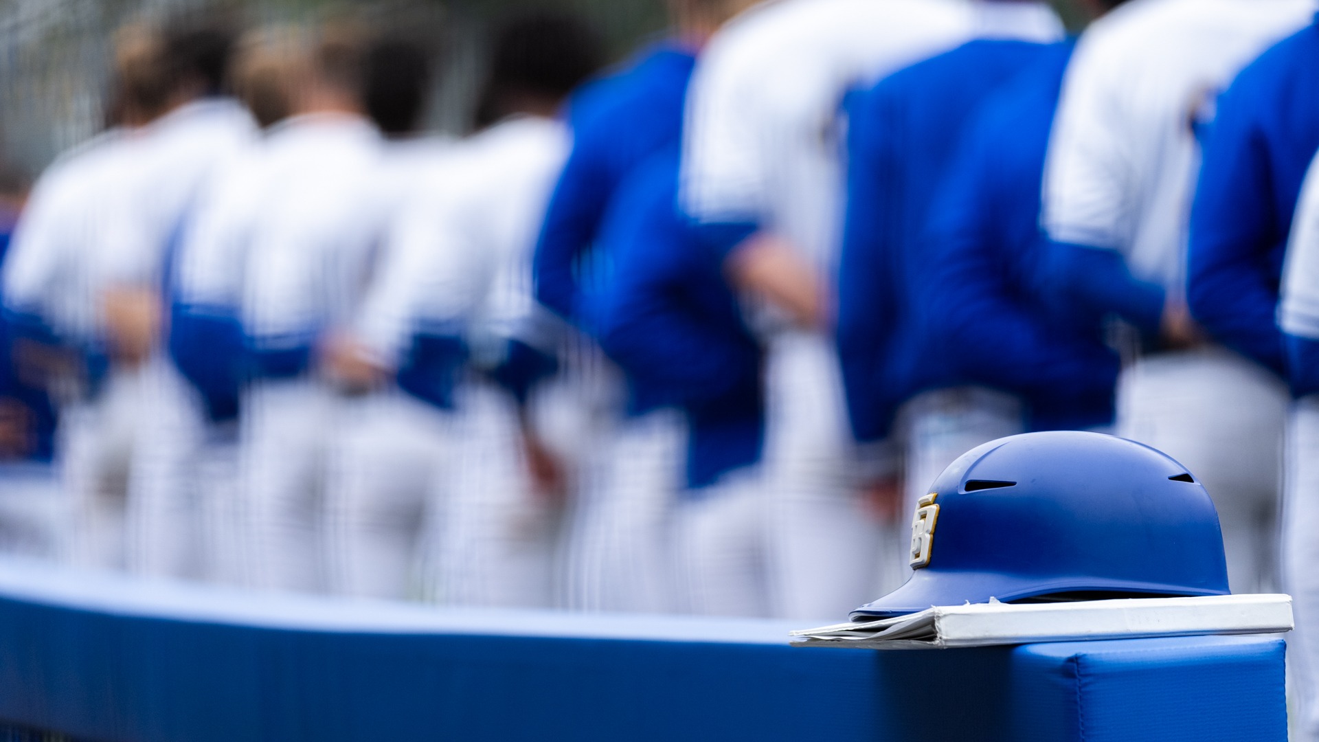 A coach's helmet rests on the dugout rail at Caesar Uyesaka Stadium