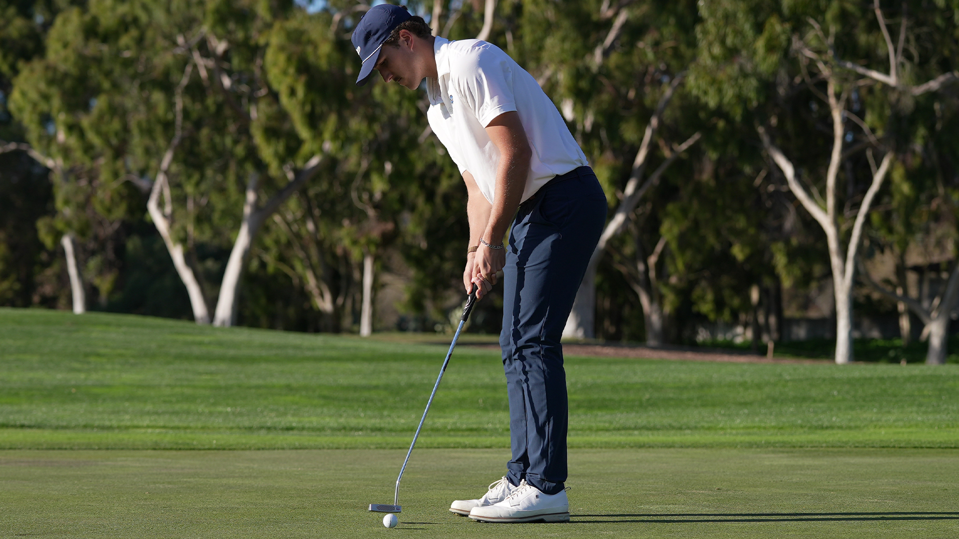 Sophomore Jack Watters hits a put on the green. The ball is rolling at the camera with Watters finishing his stroke.