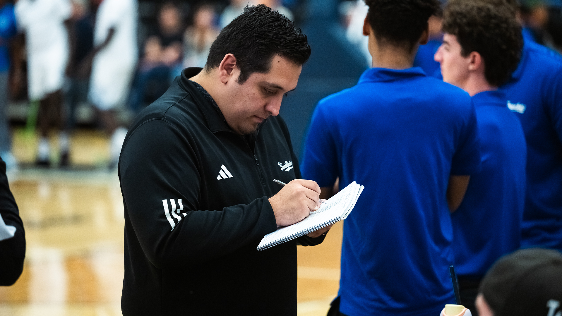 Men's Basketball Director of Operations and Recruiting, Andrew Payne, marks starters in the official scorebook prior to a game.