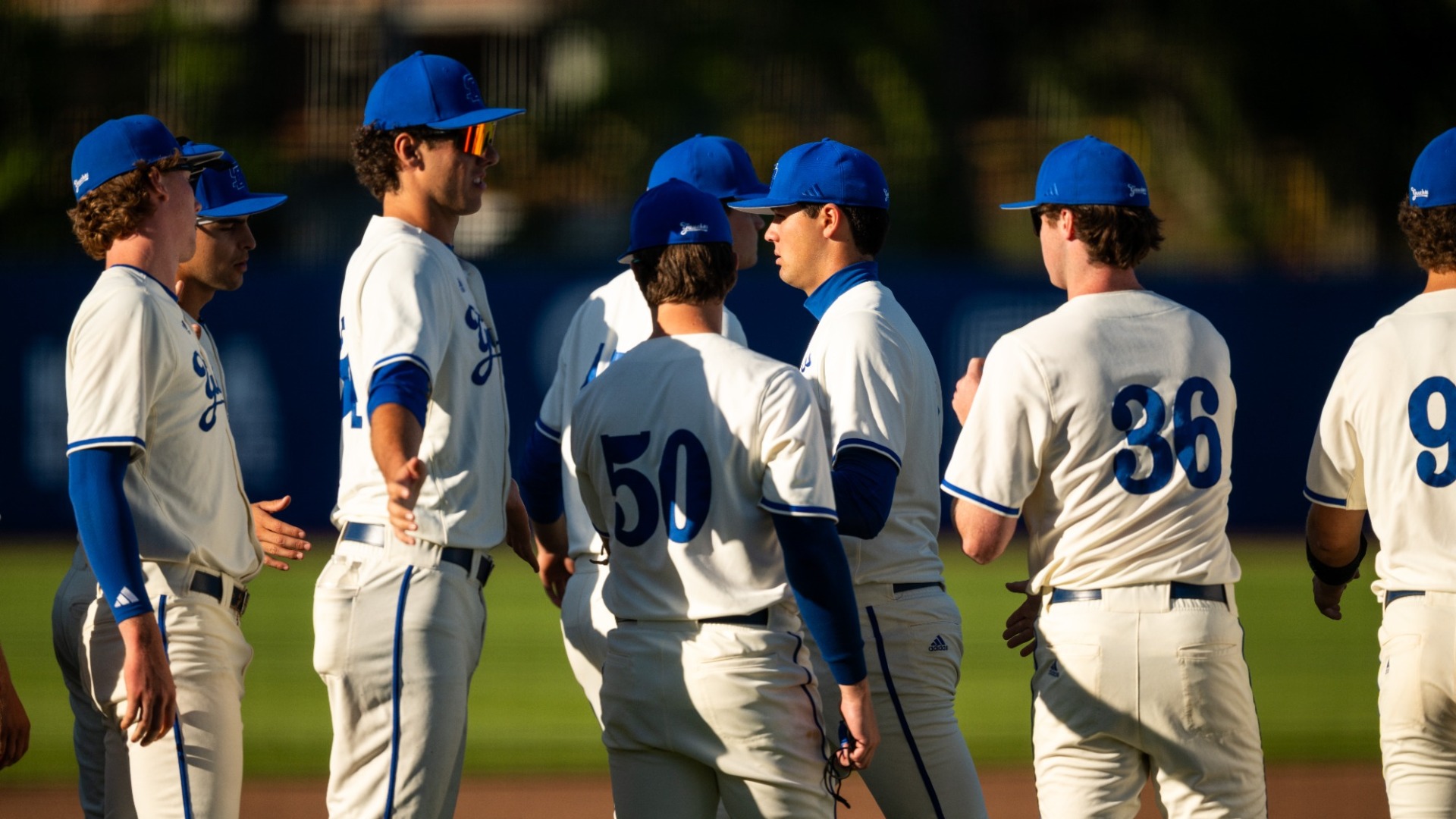 Jackson Flora (#2) receives high-fives from his teammates as he walks back to the dugout. He is walking from right to left in our frame, and is flanked by teammates on both sides