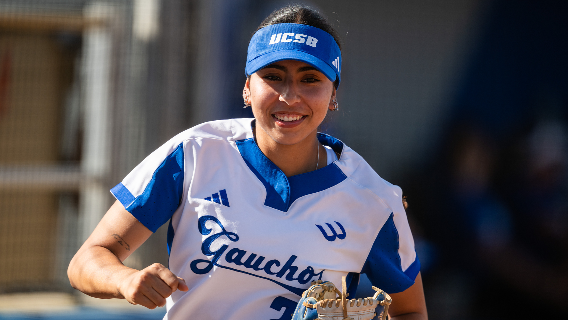 #24 Jaelyn Toledo jogs out to her first base position with her glove tucked and a smile on her face.
