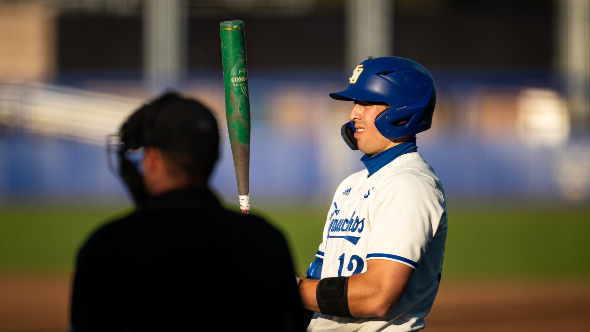 Nate Vargas (#12) stares at the barrel of his bat held out in front of him, focusing himself as he prepares to hit.