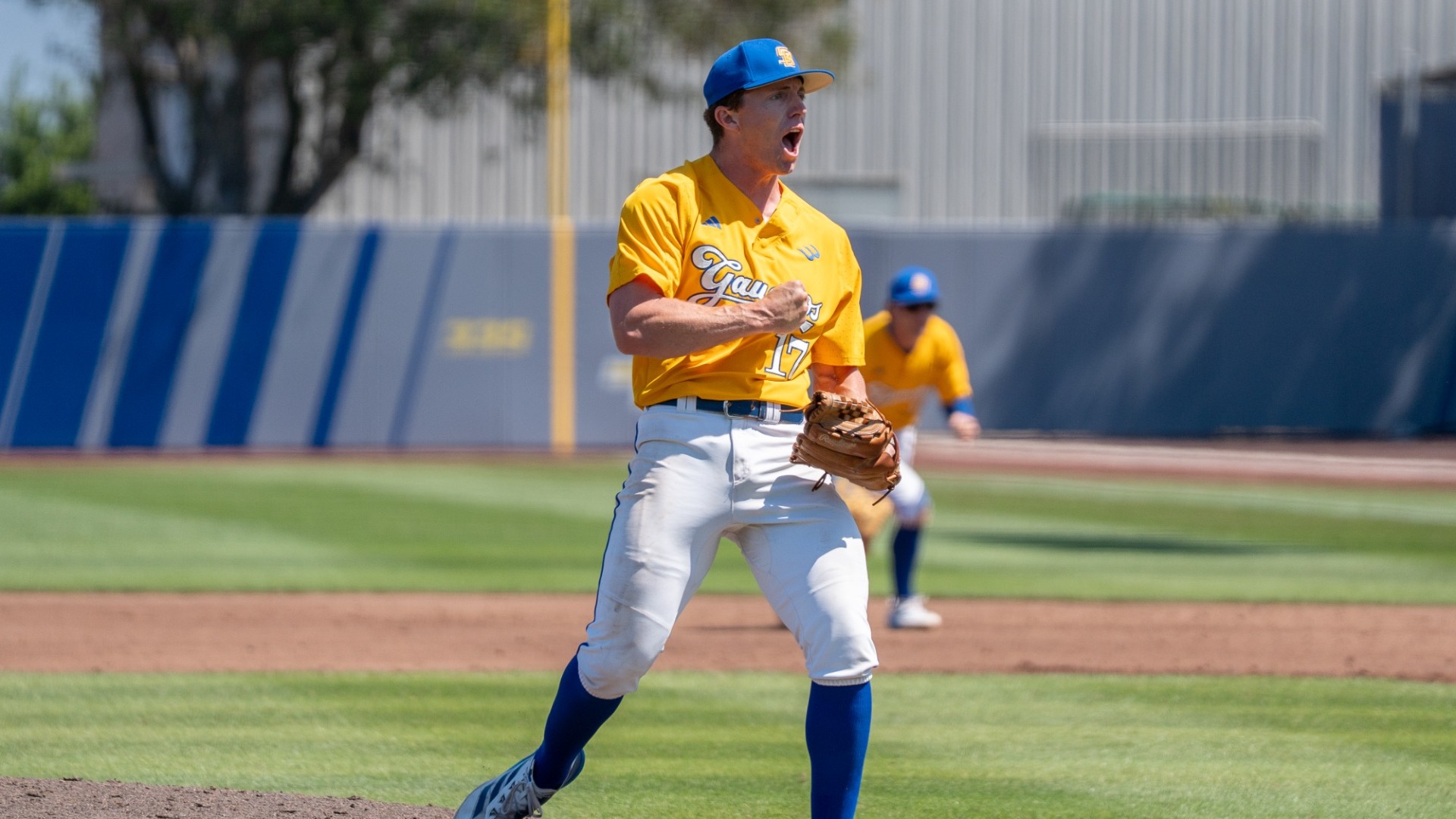 Kellan Montgomery (#17) yells in celebration after recording an out. From just in front of the pitcher's mound, he bangs his chest with his right hand.