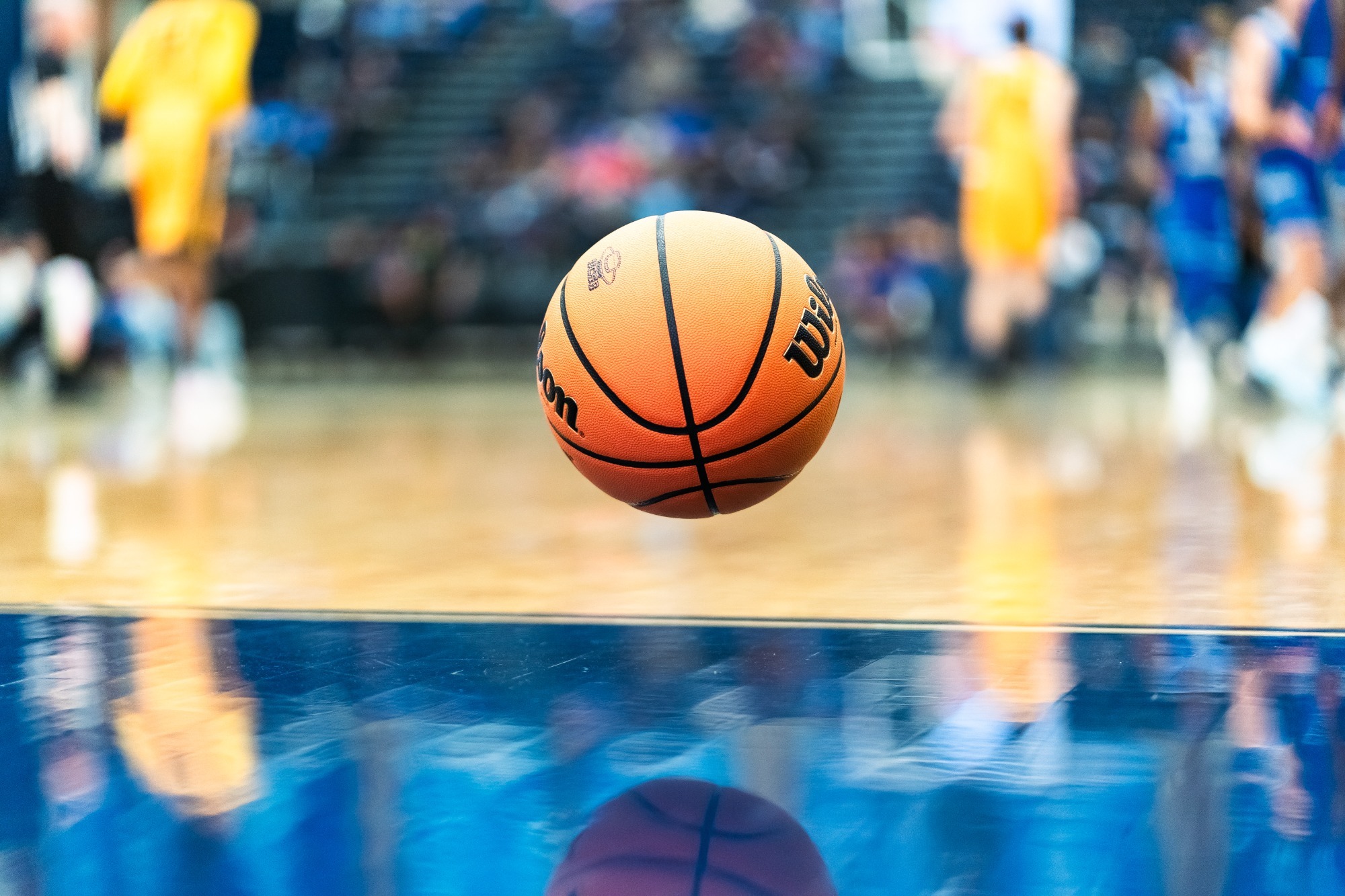 A basketball floats just above the gym floor