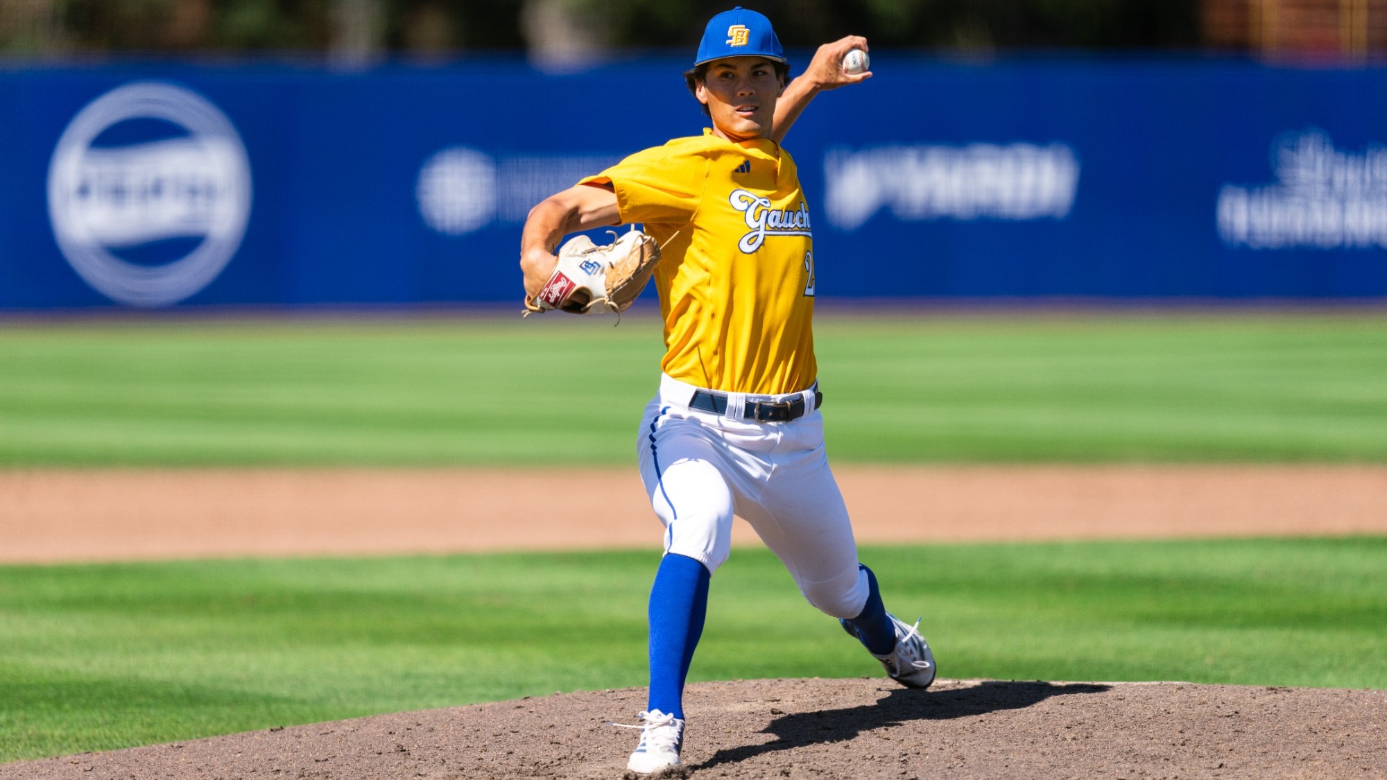 Van Froling (#24) delivers a pitch against Oregon. Lunging into his delivery with his right arm and leg in front of him, he is bringing the ball past his ear with his left hand, about to release it.