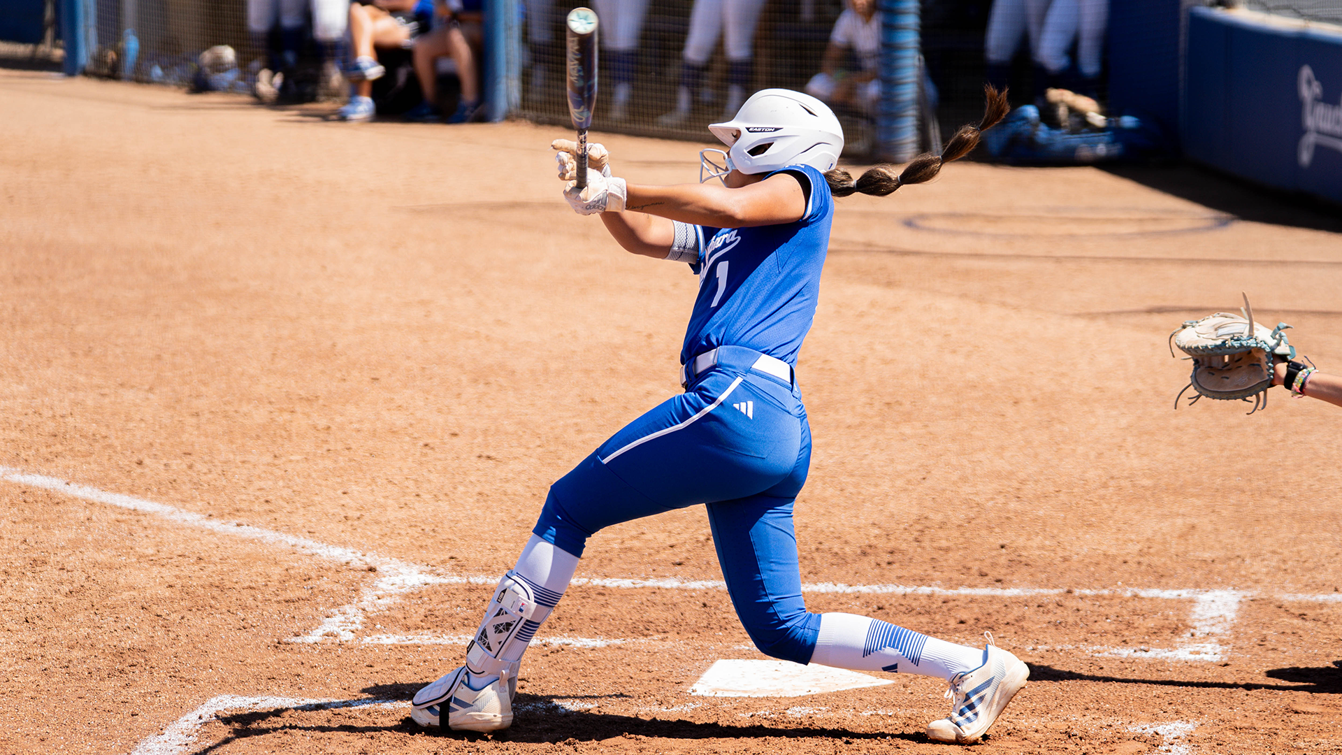 Shortstop Tehya Banks (#1) finishes her swing. Her back is turned toward the catcher with her hands finished high above her shoulders. 