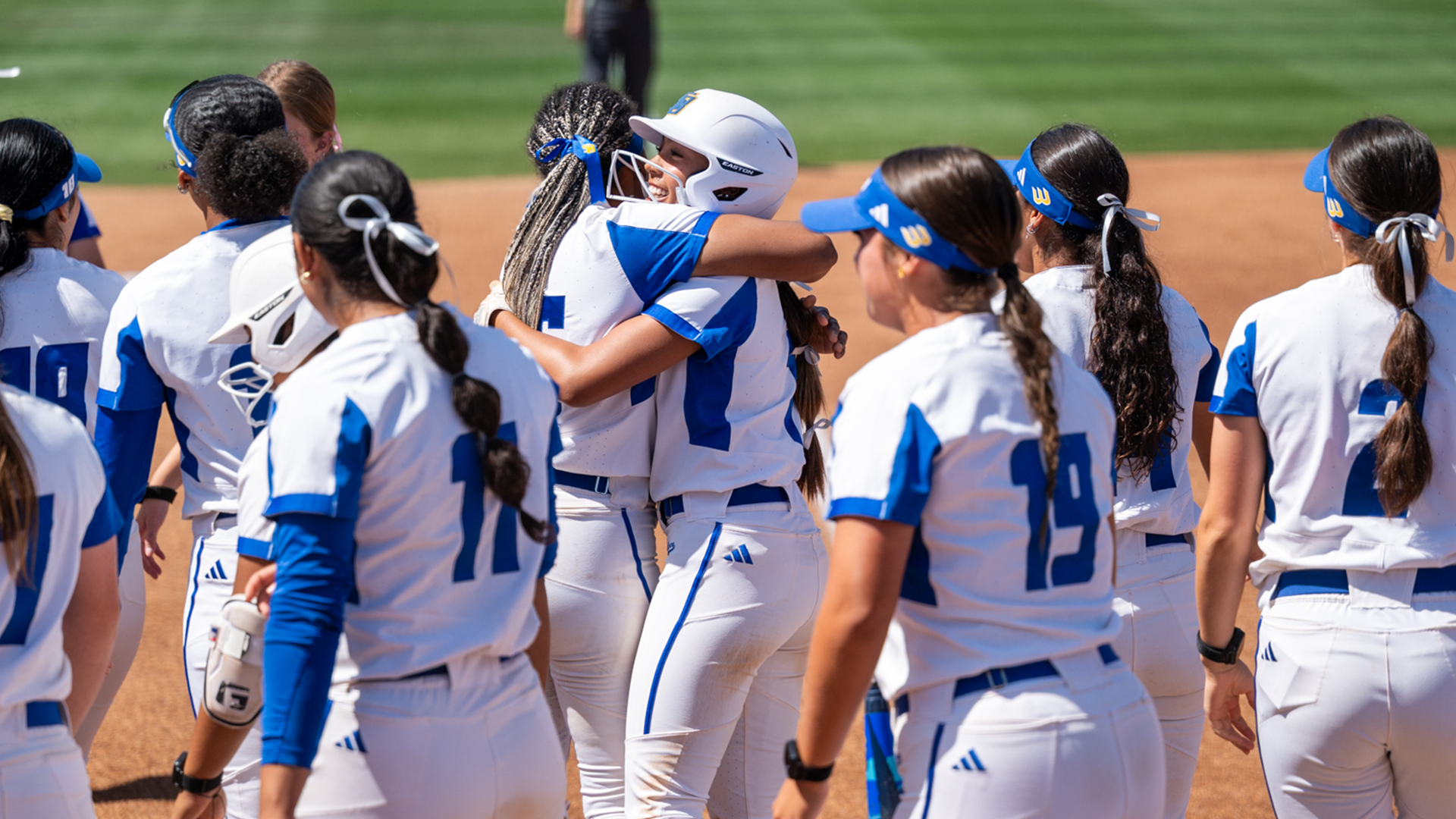 Malaya Johnson (#55) hugs Tehya Banks (#1) after hitting a home run in the first inning of game two against CSUN. Other UCSB student-athletes are standing around waiting to celebrate with Tehya.