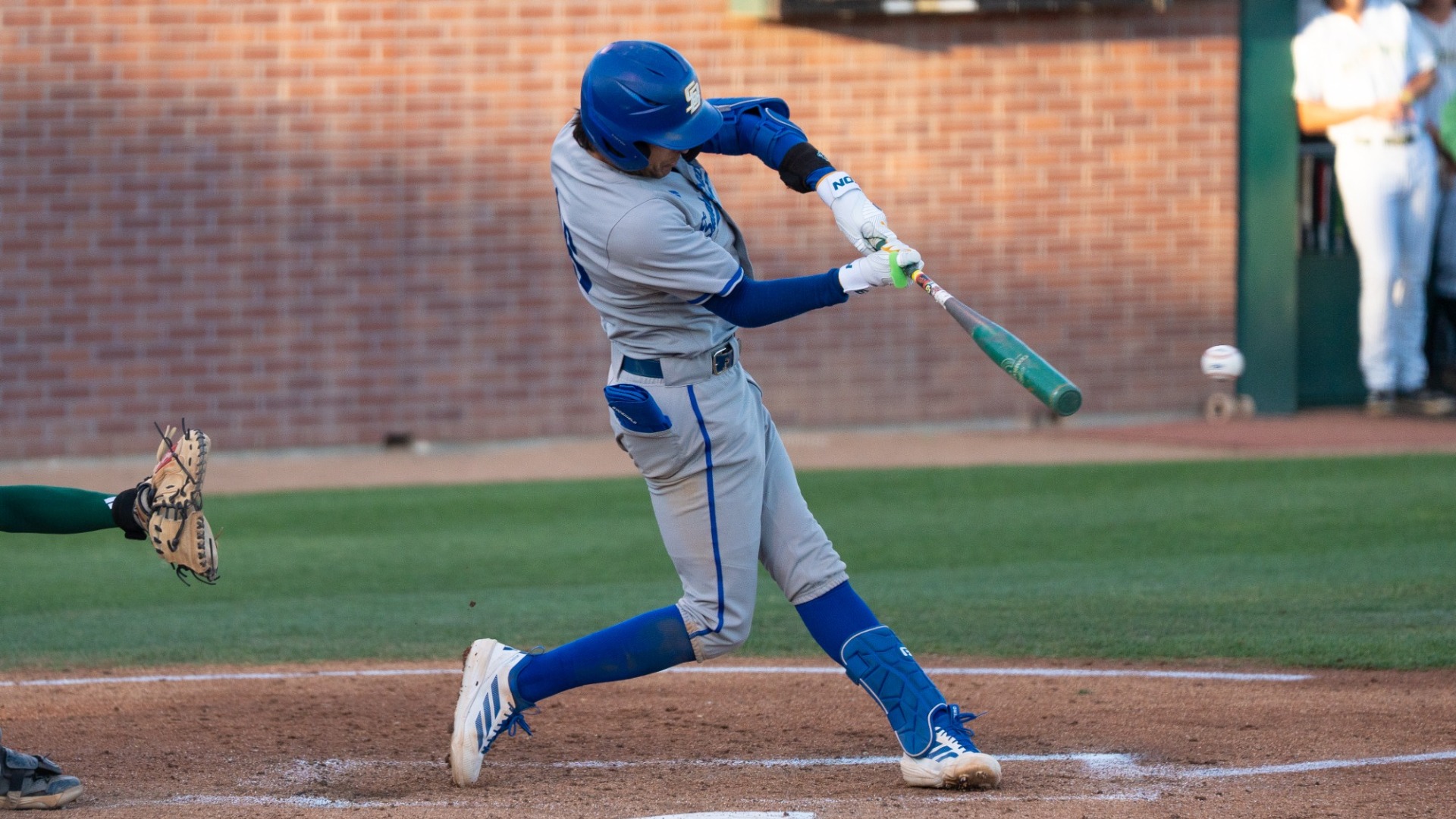 Ryan Severns (#46) swings at a pitch in the Gauchos' game at Cal Poly. His back leg is bent as he drives his hips through the swing. We can see a blurry baseball flying in front of his bat.
