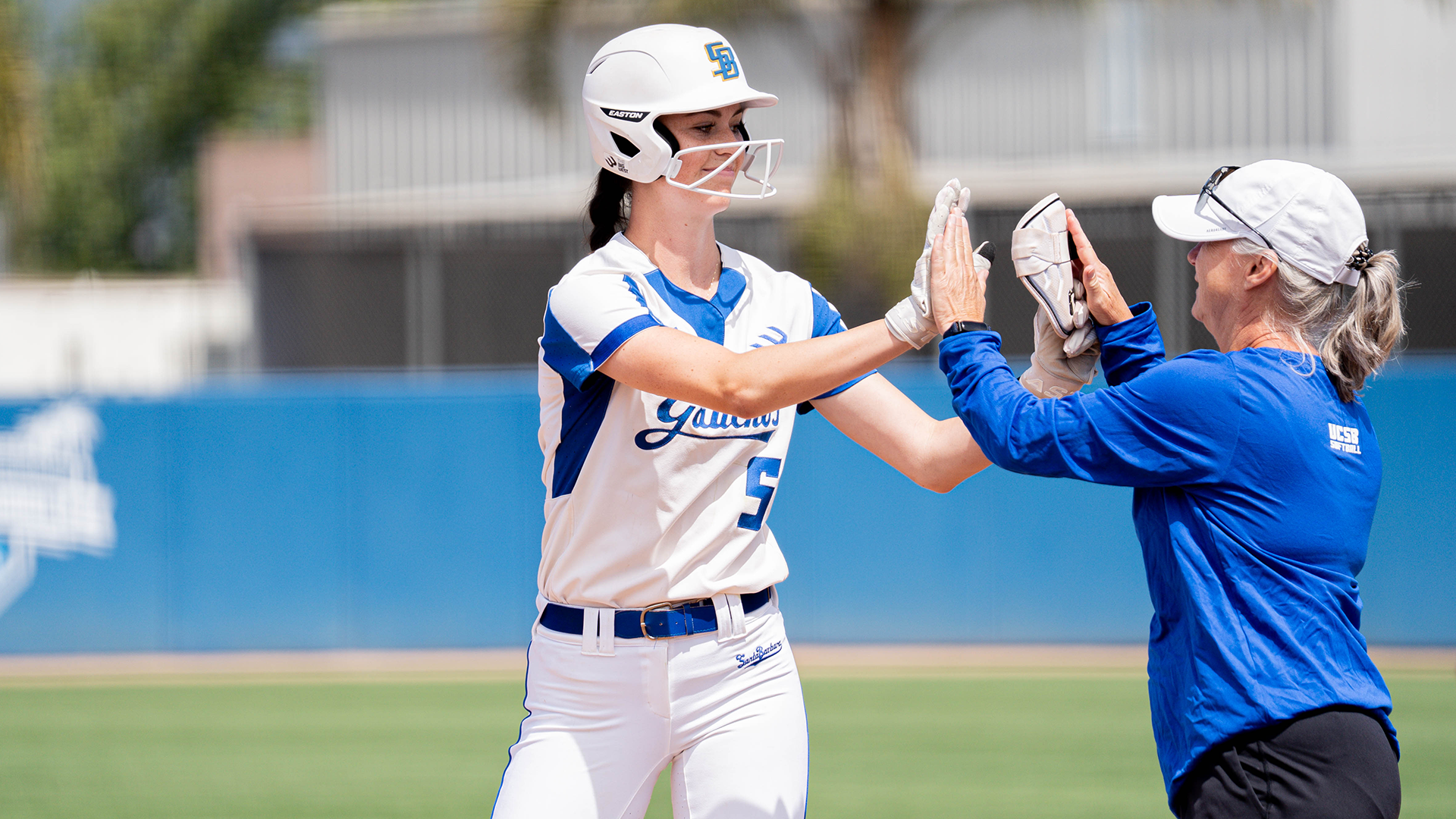 #5 Dani Rauscher gives a high five to first base coach Joy Jackson after a hit against Hawai'i.