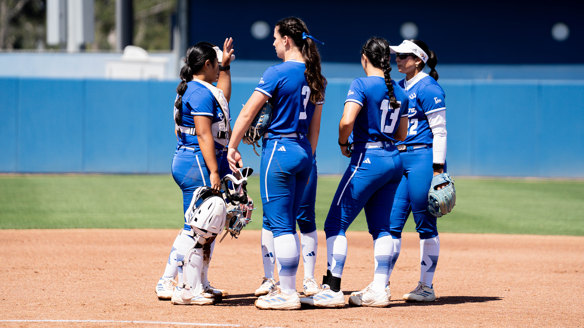 Delaina Ma'ae, Ainsley Waddell, Jazzy Santos and Ella Myers meet at the pitchers circle and talk while a play is being reviewed. 