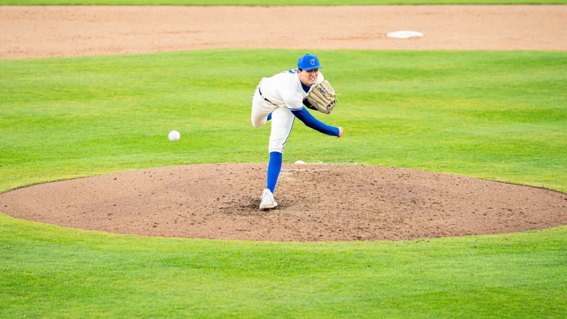 #2 Jackson Flora bends all the way forward as he delivers a pitch from the mound at Caesar Uyesaka Stadium. 