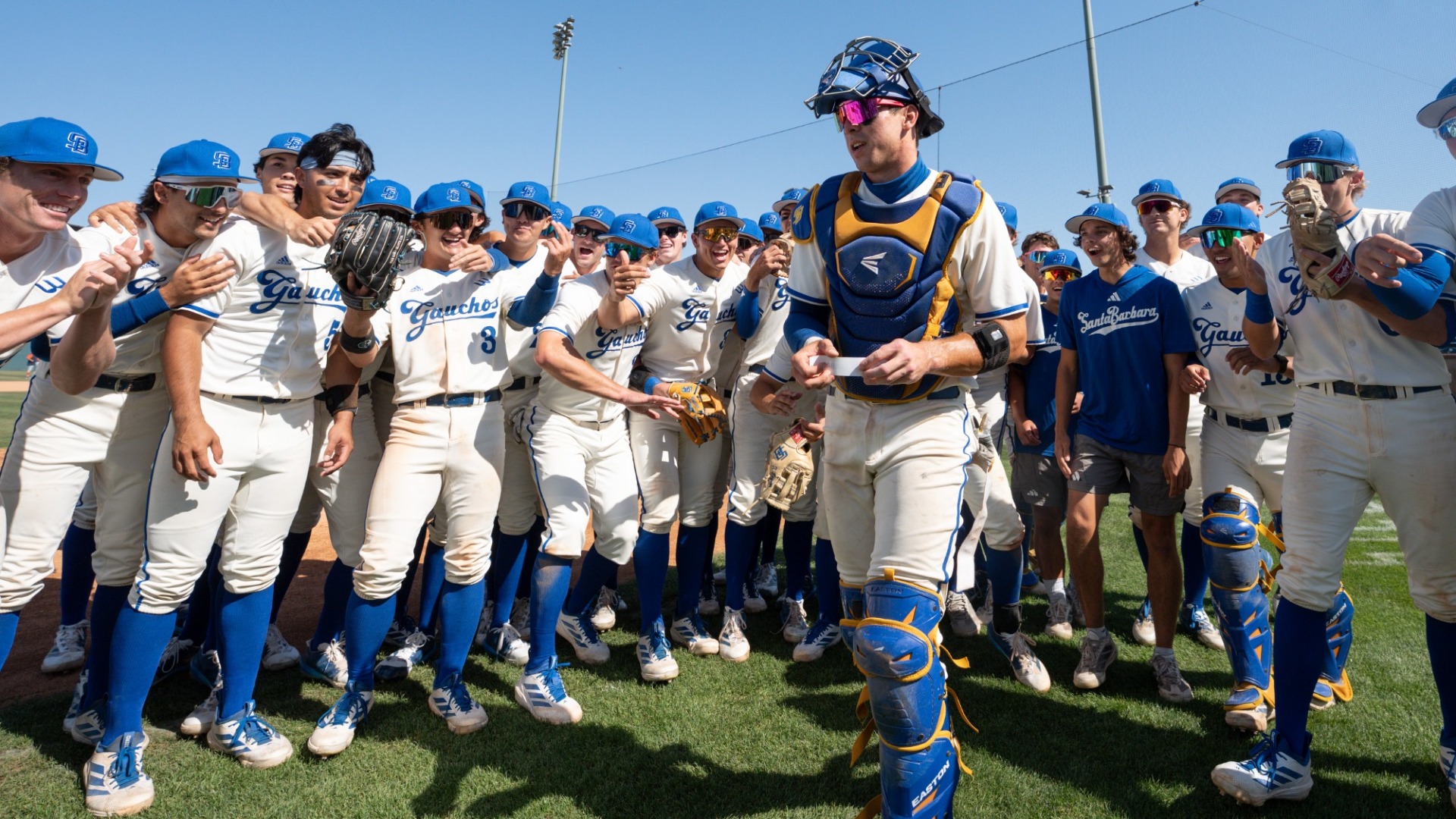 Catcher Nate Vargas prepares to place UC Santa Barbara's sticker in the next round on The Big West Championship bracket, still in all his gear and surrounded by a semicircle of teammates.