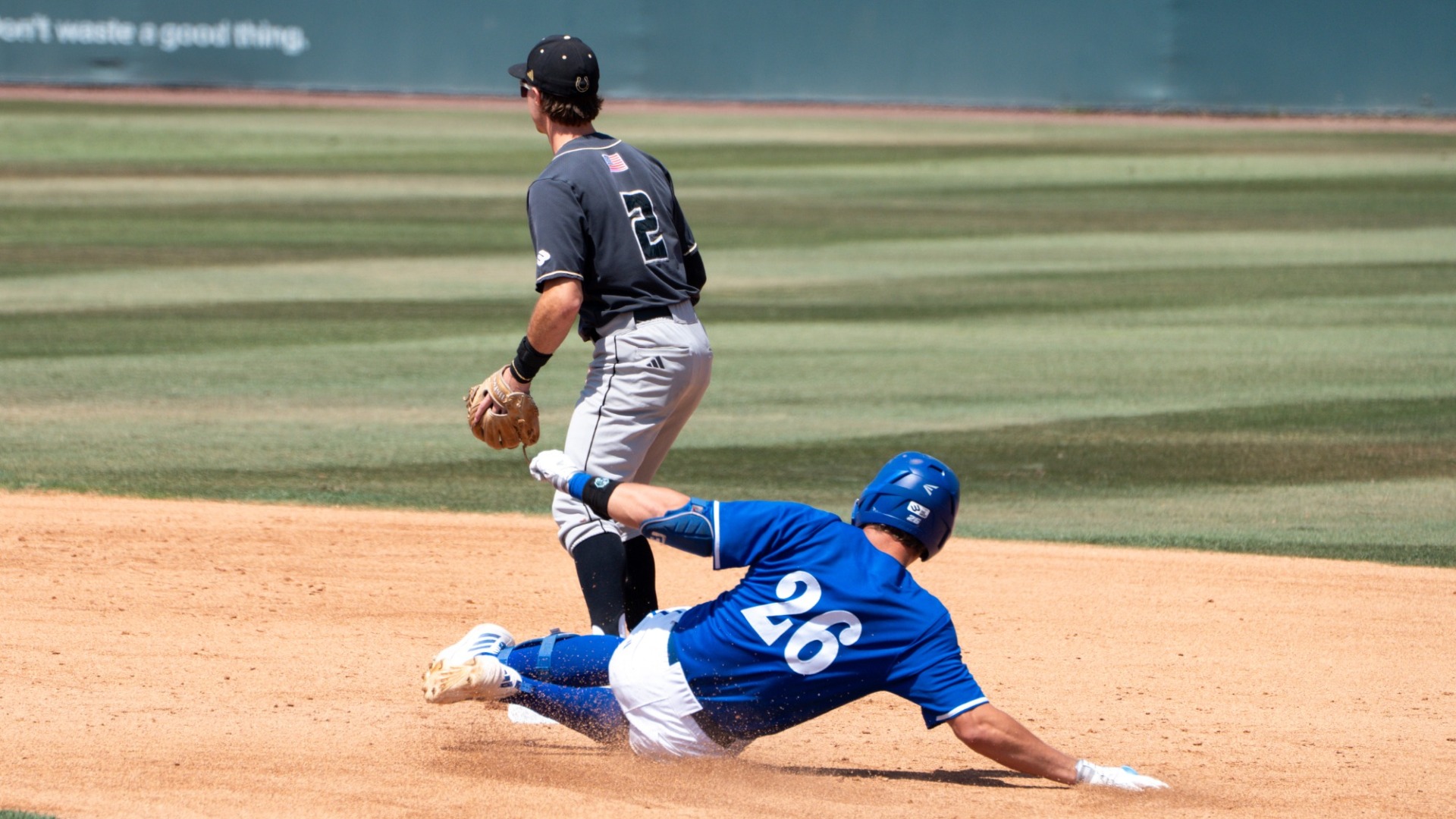 #26 William Vasseur slides into second base while a Cal Poly defender stands and looks towards left field for a throw that will be too late