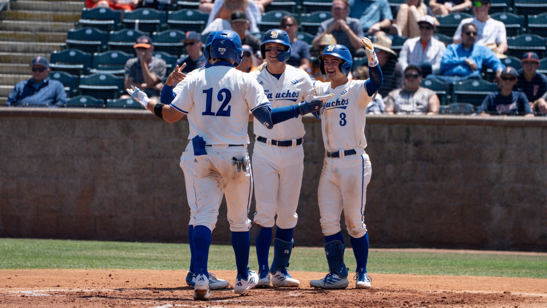 Nate Vargas is met at home plate by his teammates, with arms extended for a celebratory hug after his home run in the first round of The Big West Championship