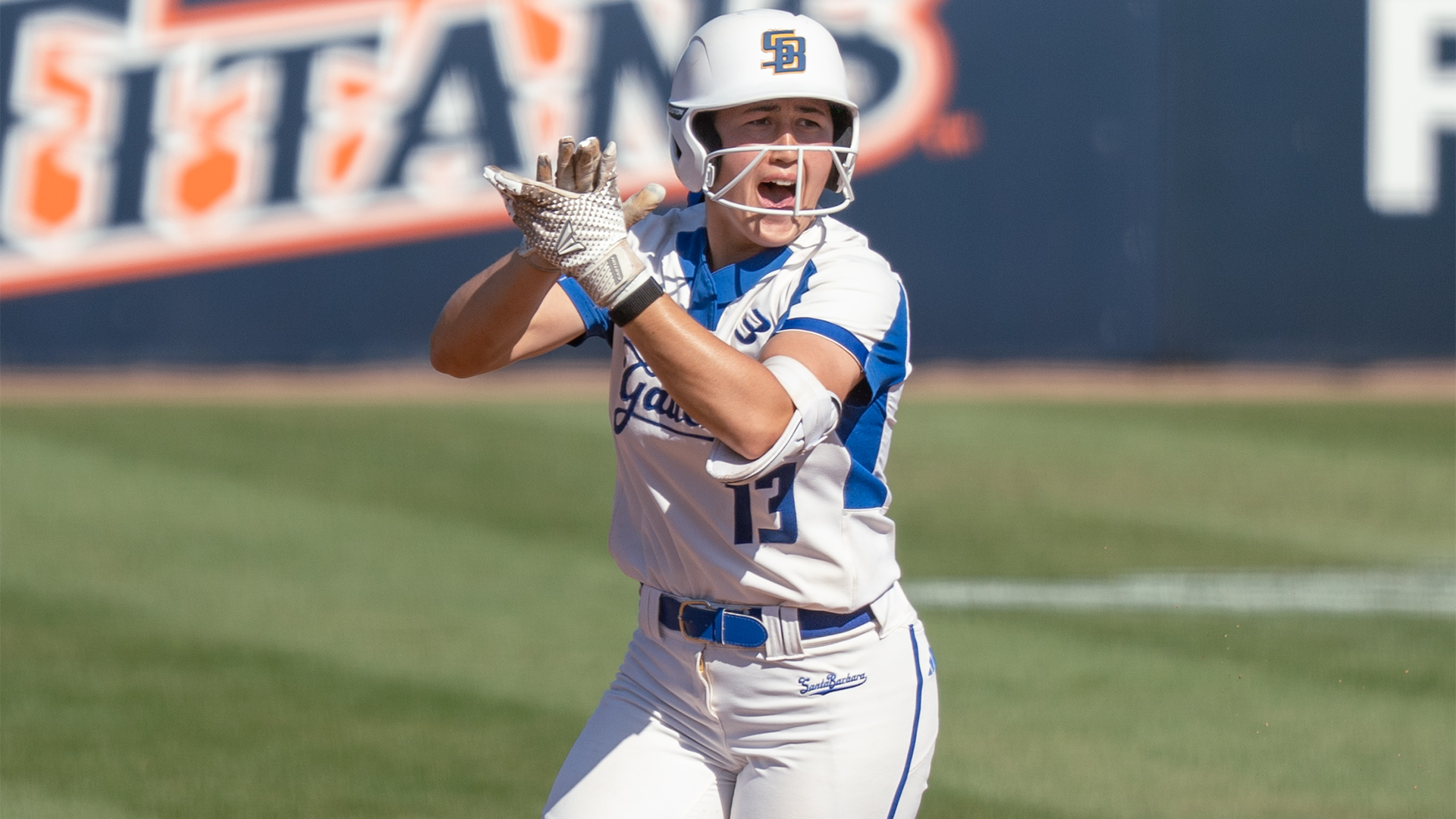 Ella Myers (#13) celebrates a home run against Long Beach State by clapping her hands above her head and cheering.
