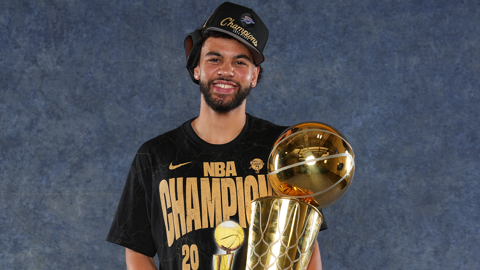Ajay Mitchell posses with the NBA Trophy after winning the 2025 NBA Championship with the Oklahoma City Thunder.
