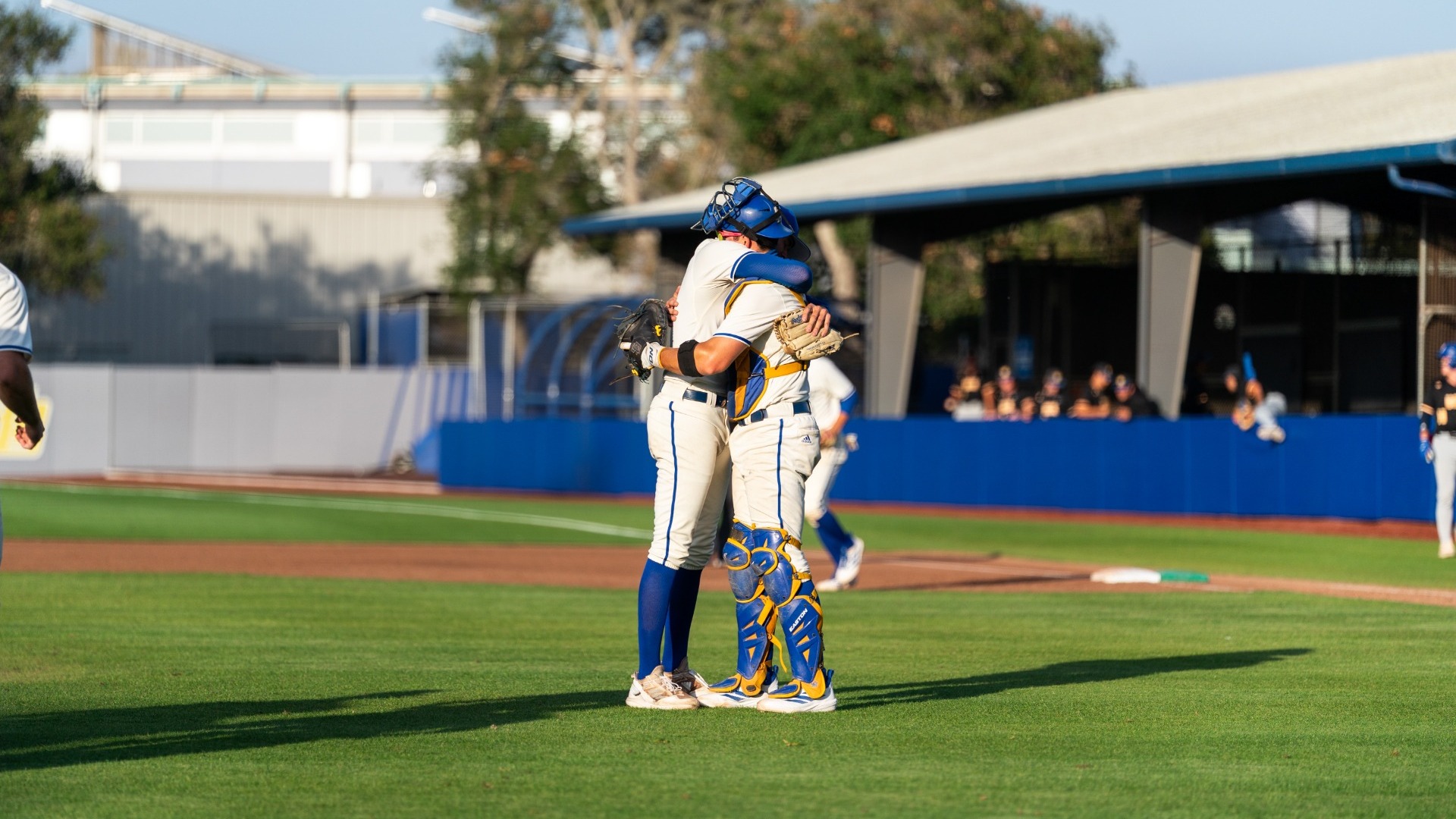 Jackson Flora and Nate Vargas hug on the grass between the mound and home plate at Caesar Uyesaka Stadium at the end of Flora's complete game against UC Riverside